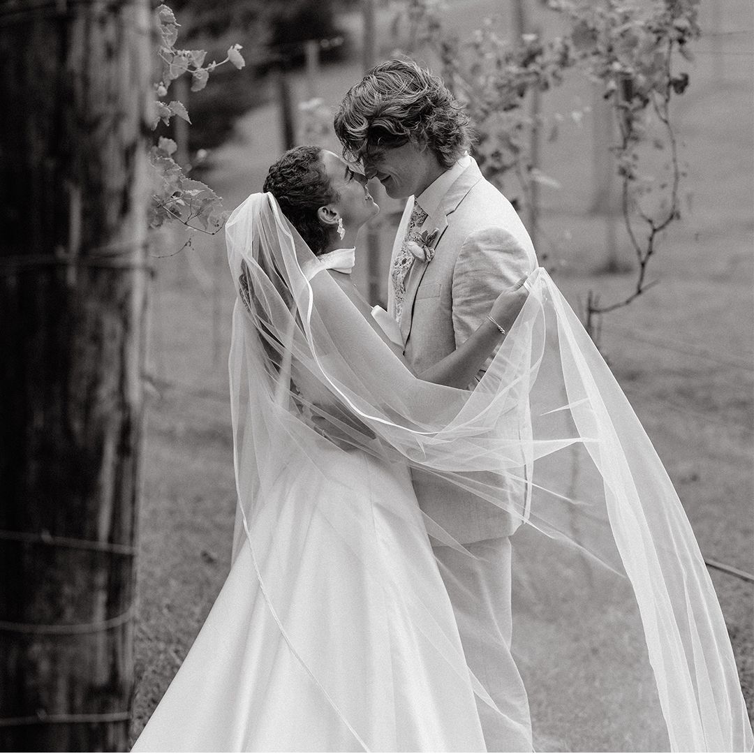 A romantic black and white wedding photo series showing a couple embracing with a flowing veil in an outdoor garden setting.