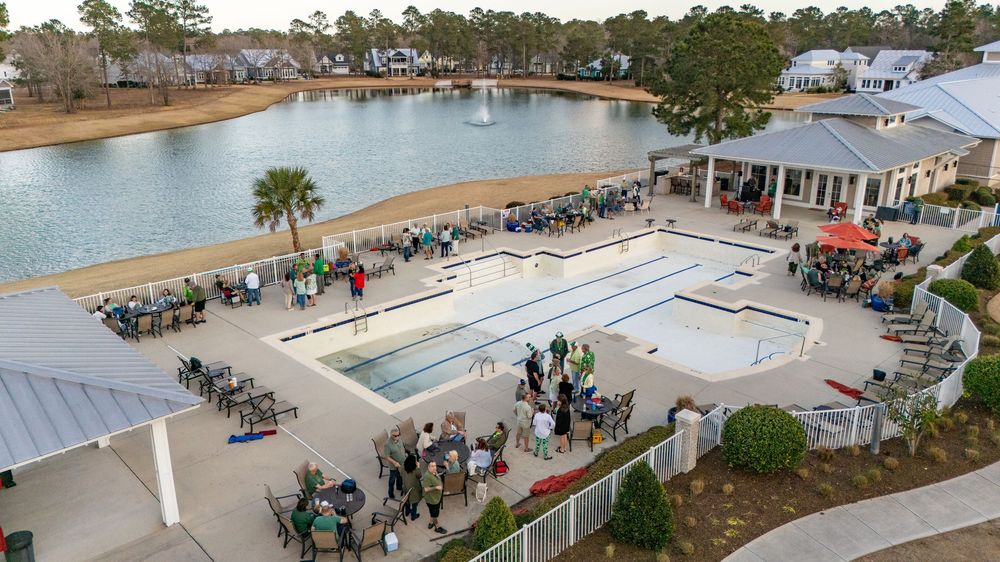 Aerial view of outdoor dining area and gathering space overlooking waterfront at coastal restaurant venue.