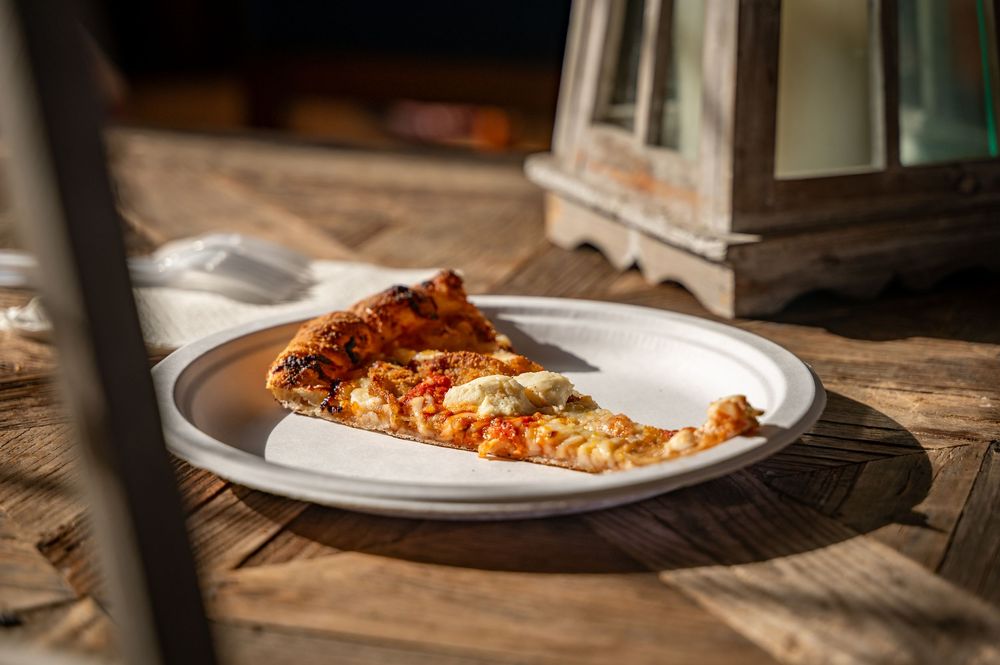 A rustic wooden table setting with plates of fresh pasta topped with sauce and garnishes in a cozy restaurant atmosphere.