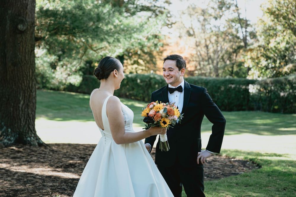 A couple in wedding attire shares a joyful moment together in a sunlit garden setting.