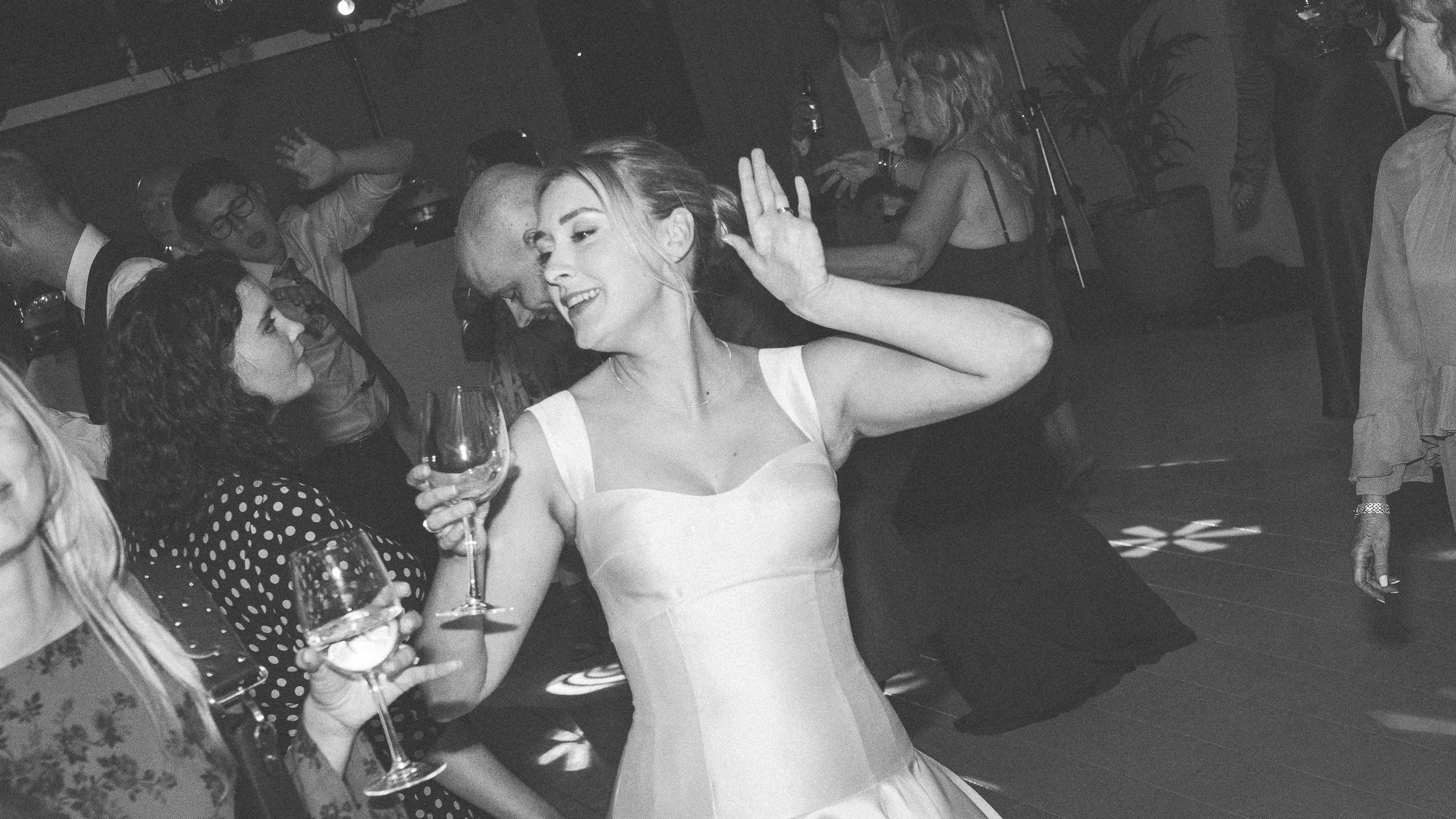 People dancing and celebrating at a lively party or wedding reception in black and white photography.