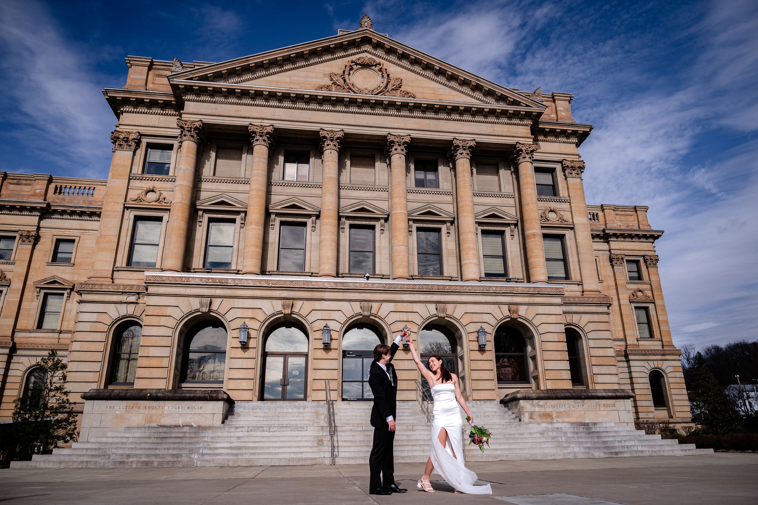 Exterior view of a grand historic government building with classical architecture and stone columns under blue sky.