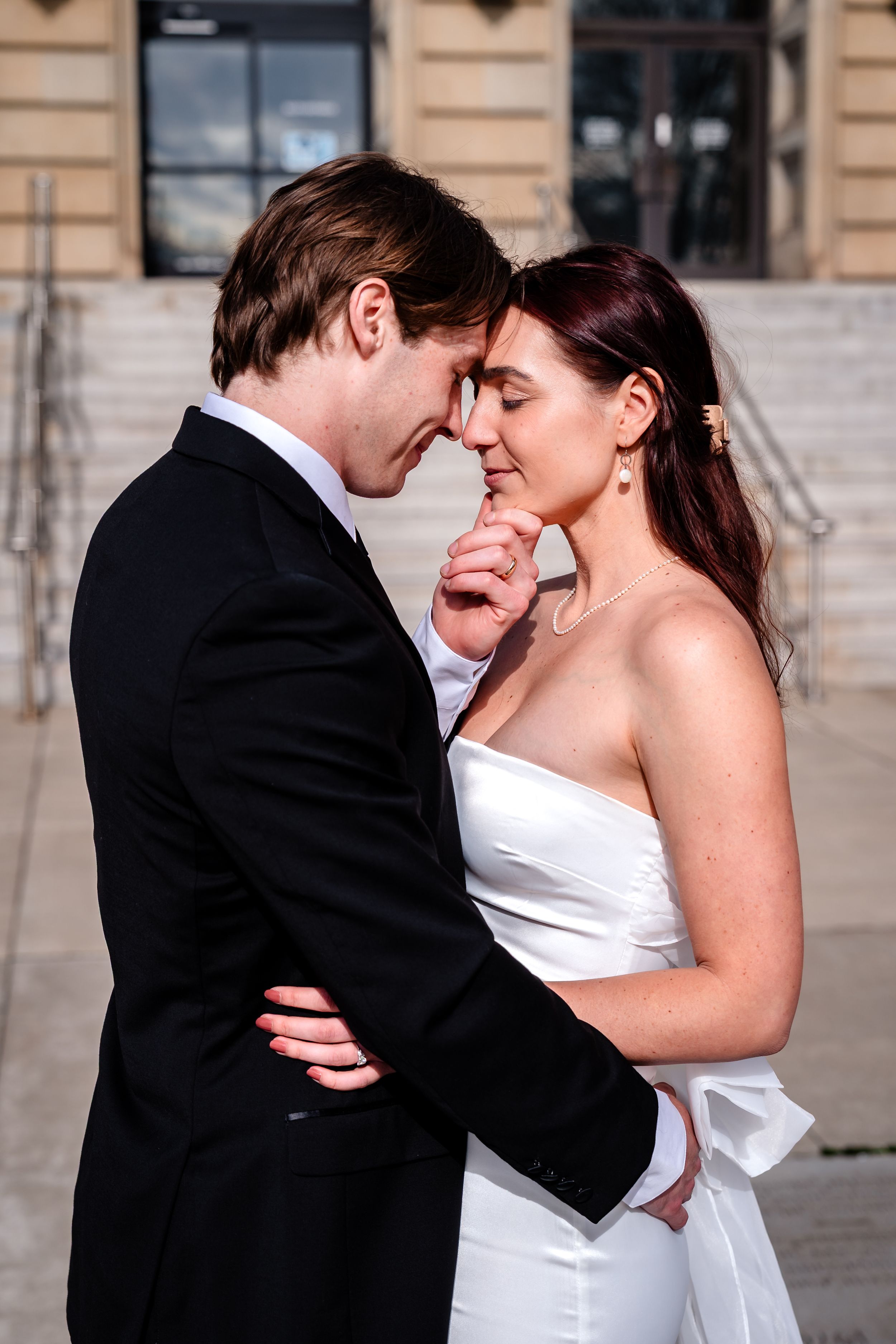 Intimate romantic moments captured between couple in formal attire outside historic building.