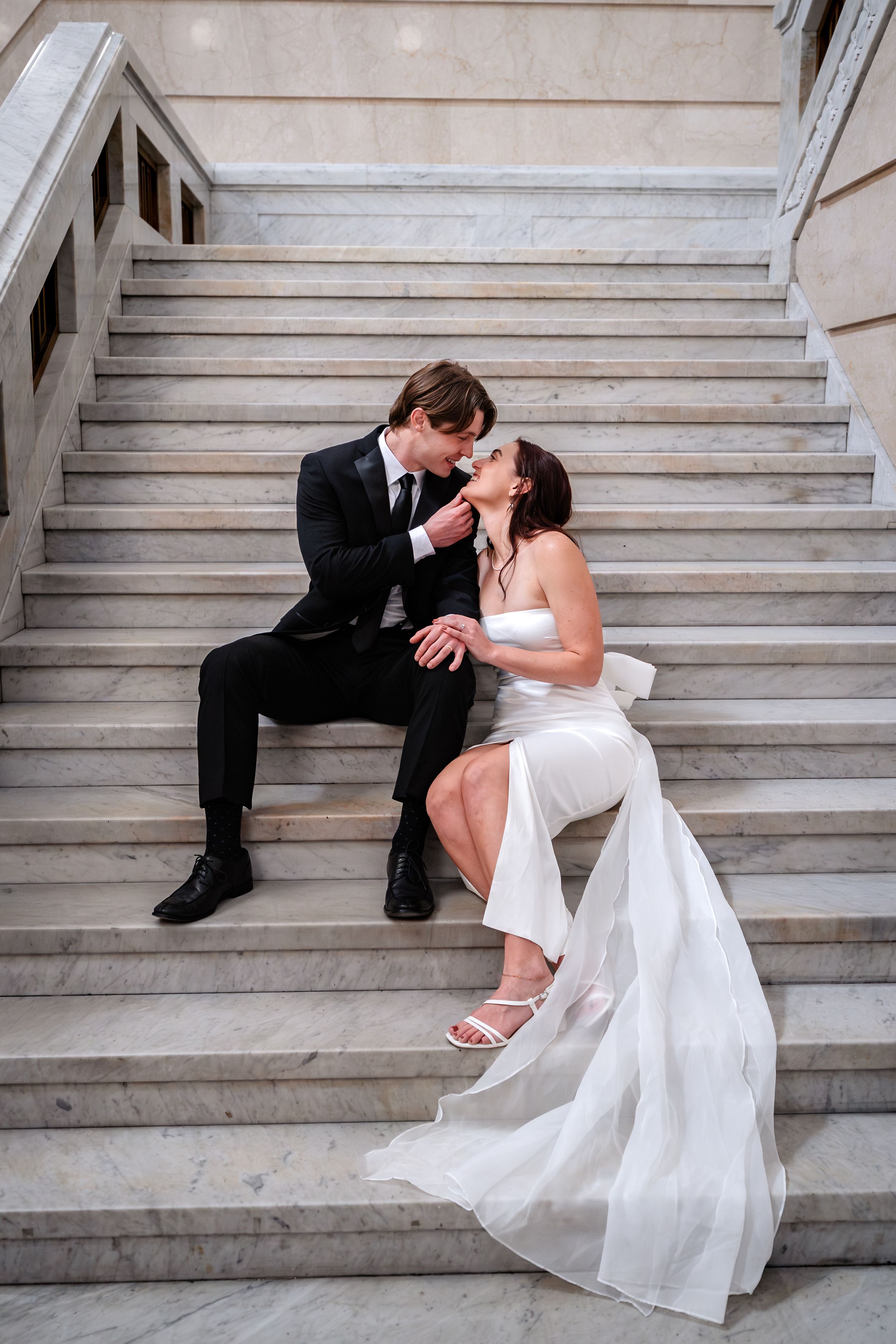 Romantic wedding couple sharing intimate moments while sitting on elegant marble steps in sequence.