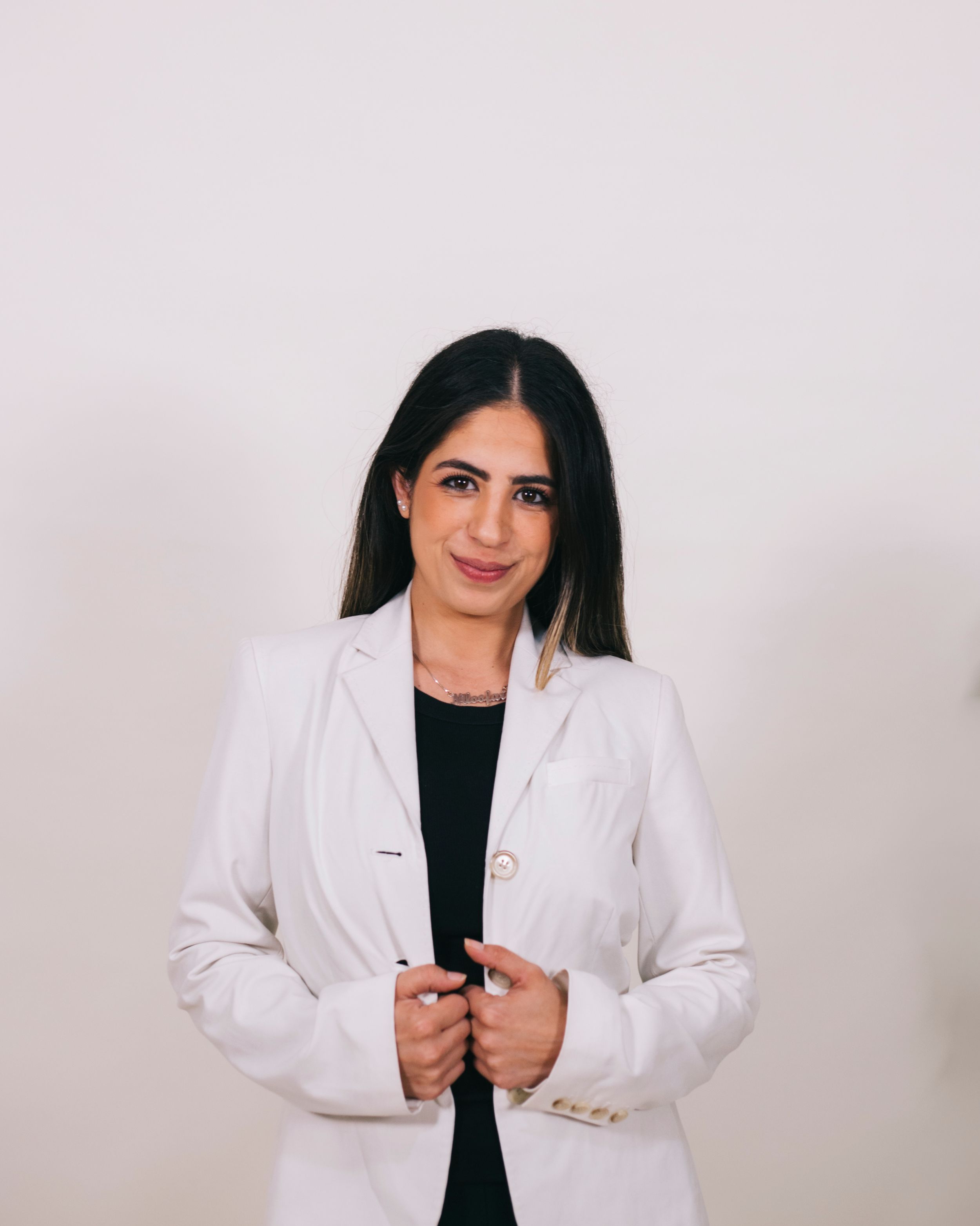 A professional woman in a white lab coat poses confidently against a clean white background.