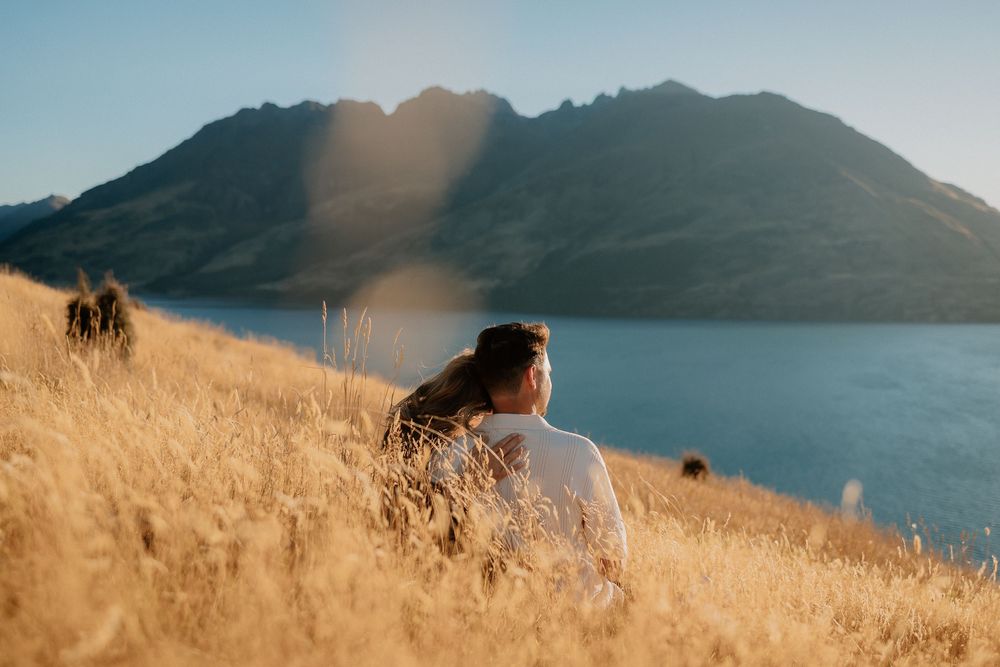 A panoramic view of golden hills overlooking a tranquil mountain lake during sunset.