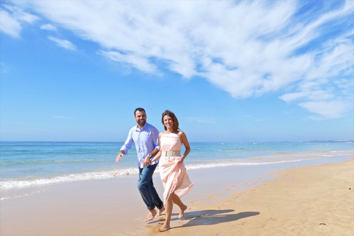 Un couple court sur une plage de l'Algarve lors d'une séance photo avant leur mariage.
