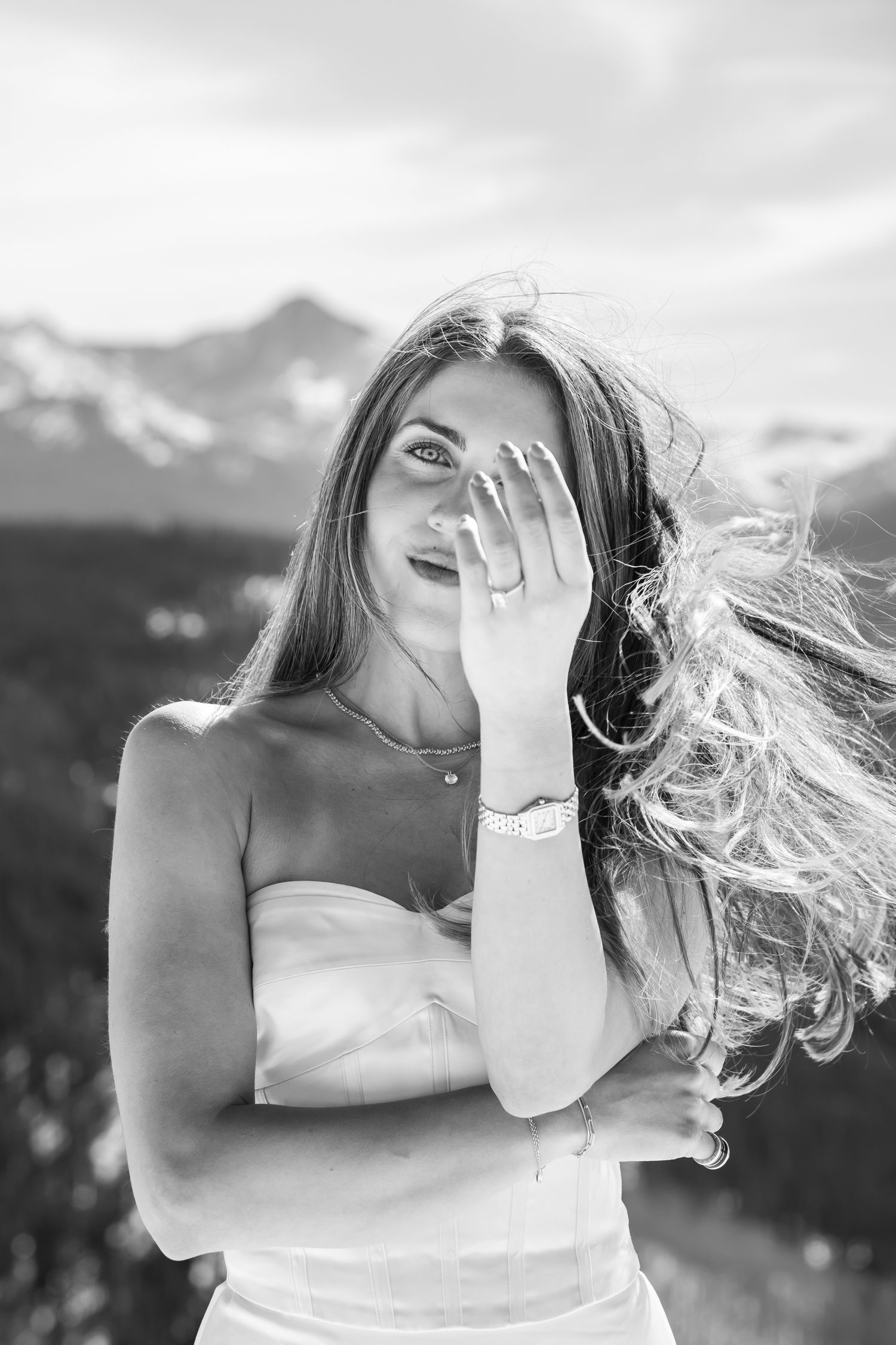 Black and white portrait of a woman with windswept hair and mountains in the background during chic engagement photos in Vail Colorado.