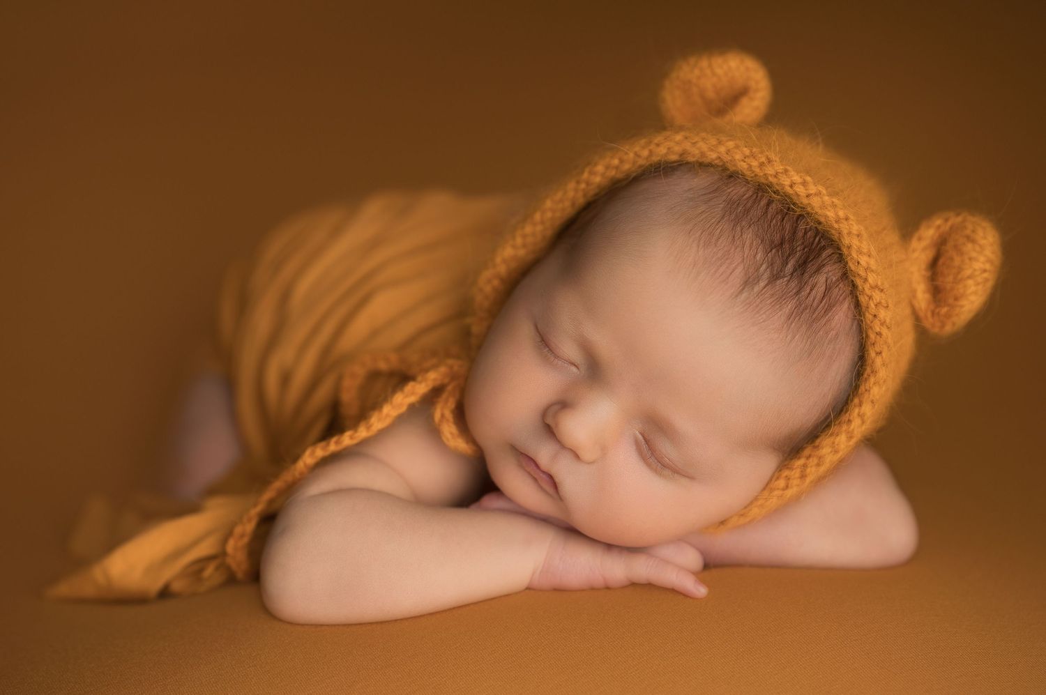 Sleeping newborn baby dressed in red Christmas outfit and knit Santa hat on fluffy white blanket.