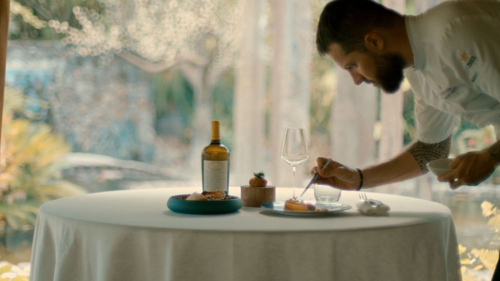 People dining at a restaurant with white tablecloths and elegant table settings in a sophisticated atmosphere.