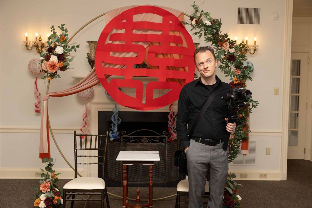 A banquet hall decorated for a Chinese wedding celebration with red double happiness symbols and floral arrangements.