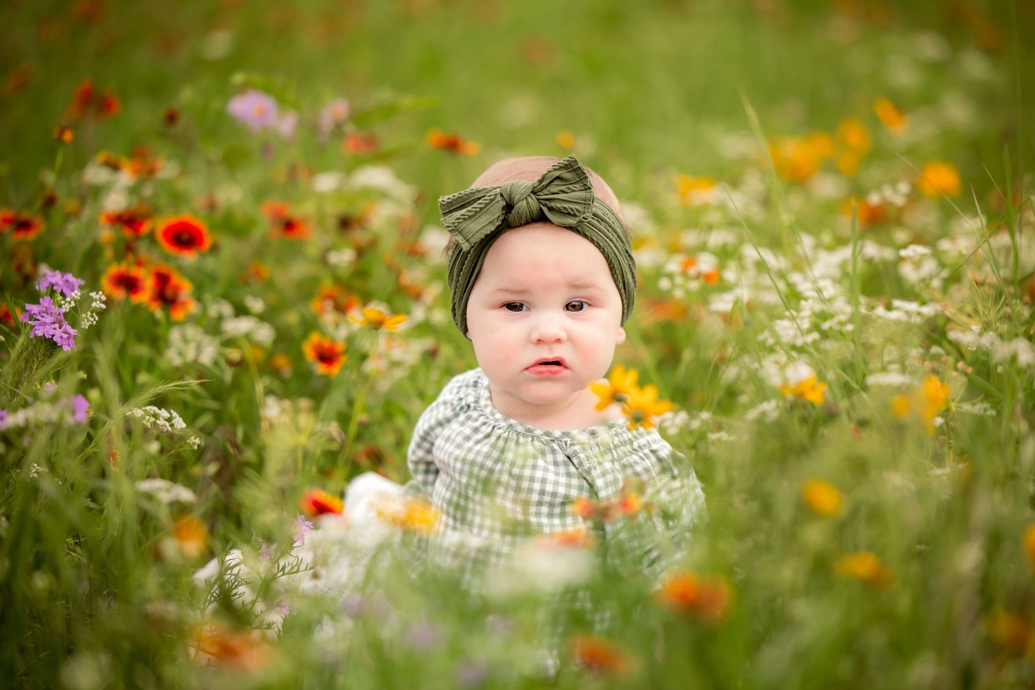 Toddler sits in a colorful wildflower meadow surrounded by flowers in Fort Worth, TX.