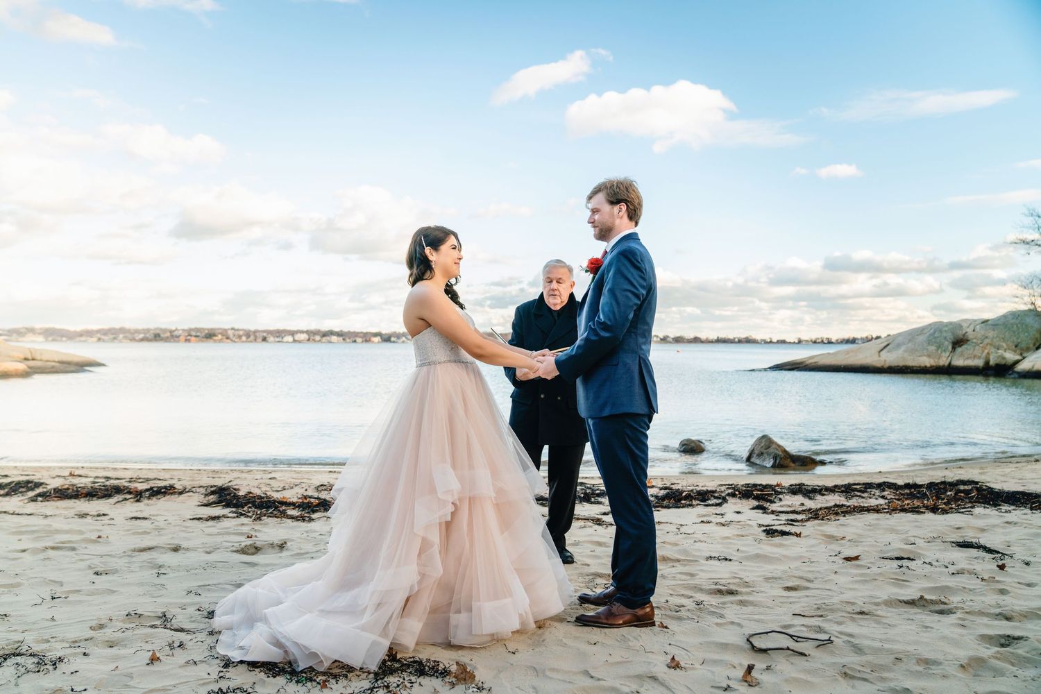 Couple on the beach during their wedding ceremony in Gloucester, Massachusetts.