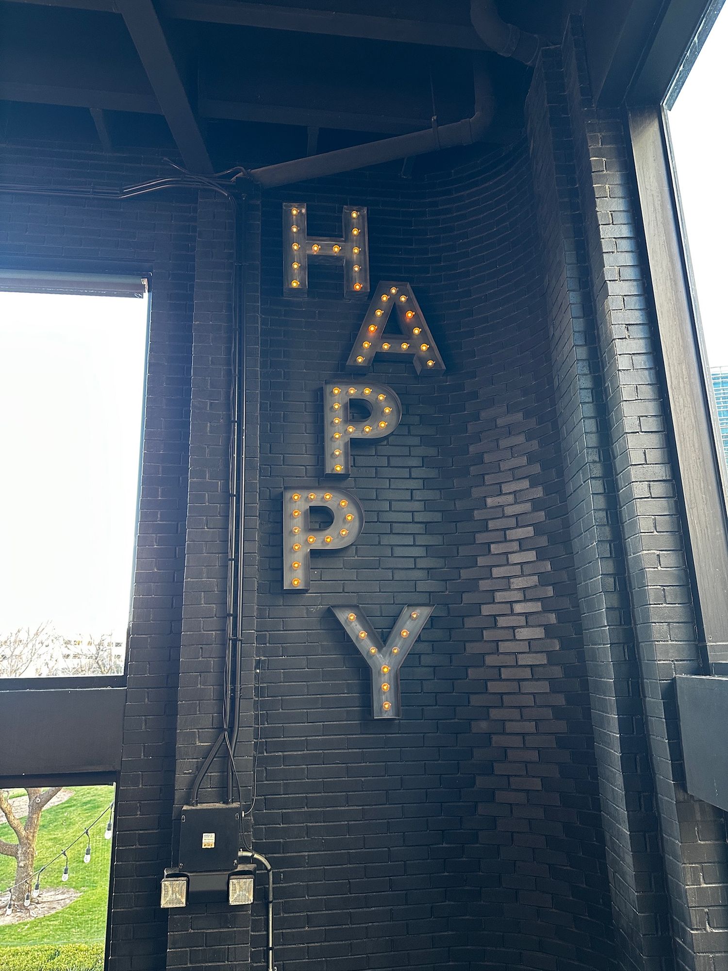 Black painted brick wall with illuminated marquee letters spelling out 'PVD' in a dark industrial space.