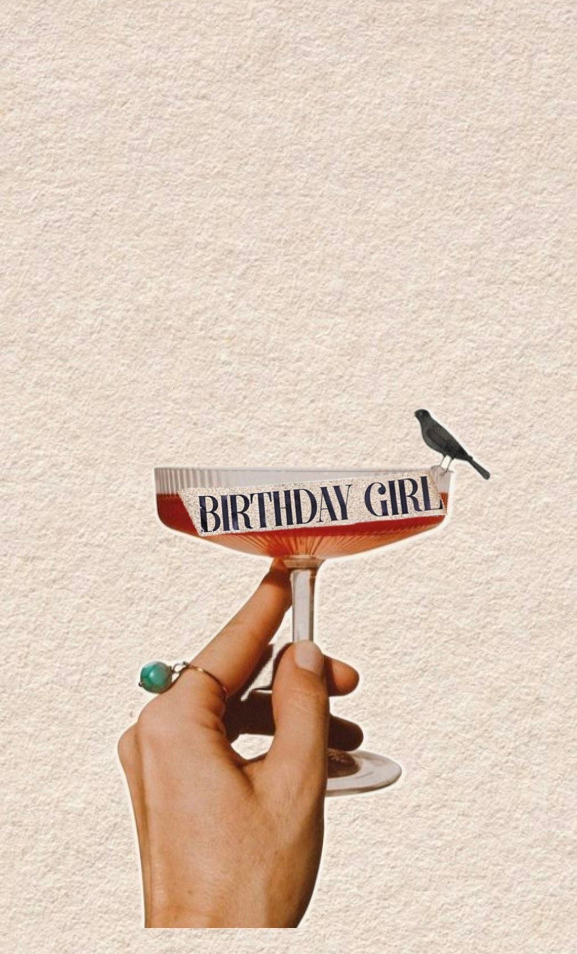 A hand holds up a decorative 'Birthday Girl' banner or sash against a beige textured background.