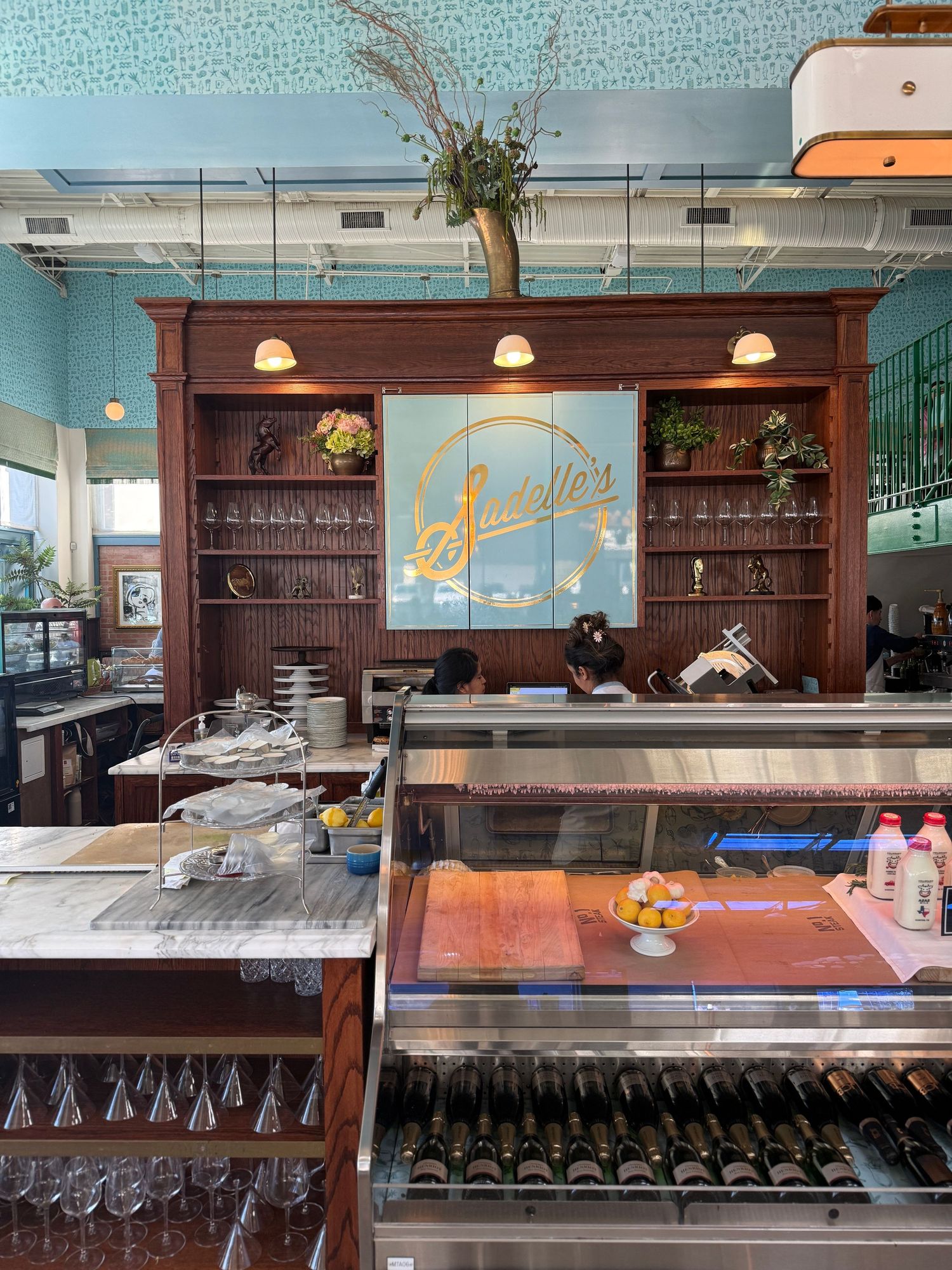 Modern bar interior with dark wood shelving, glassware displays, and polished countertops in a minimalist setting.