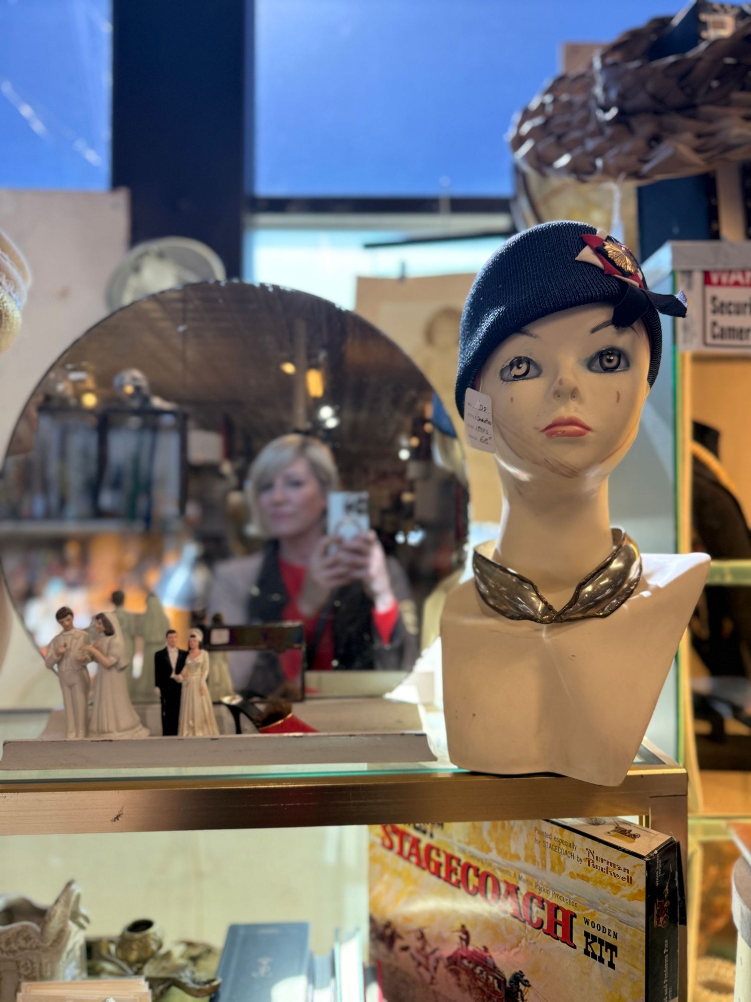 Display of white mannequin heads with painted features and wigs arranged in a retail setting.