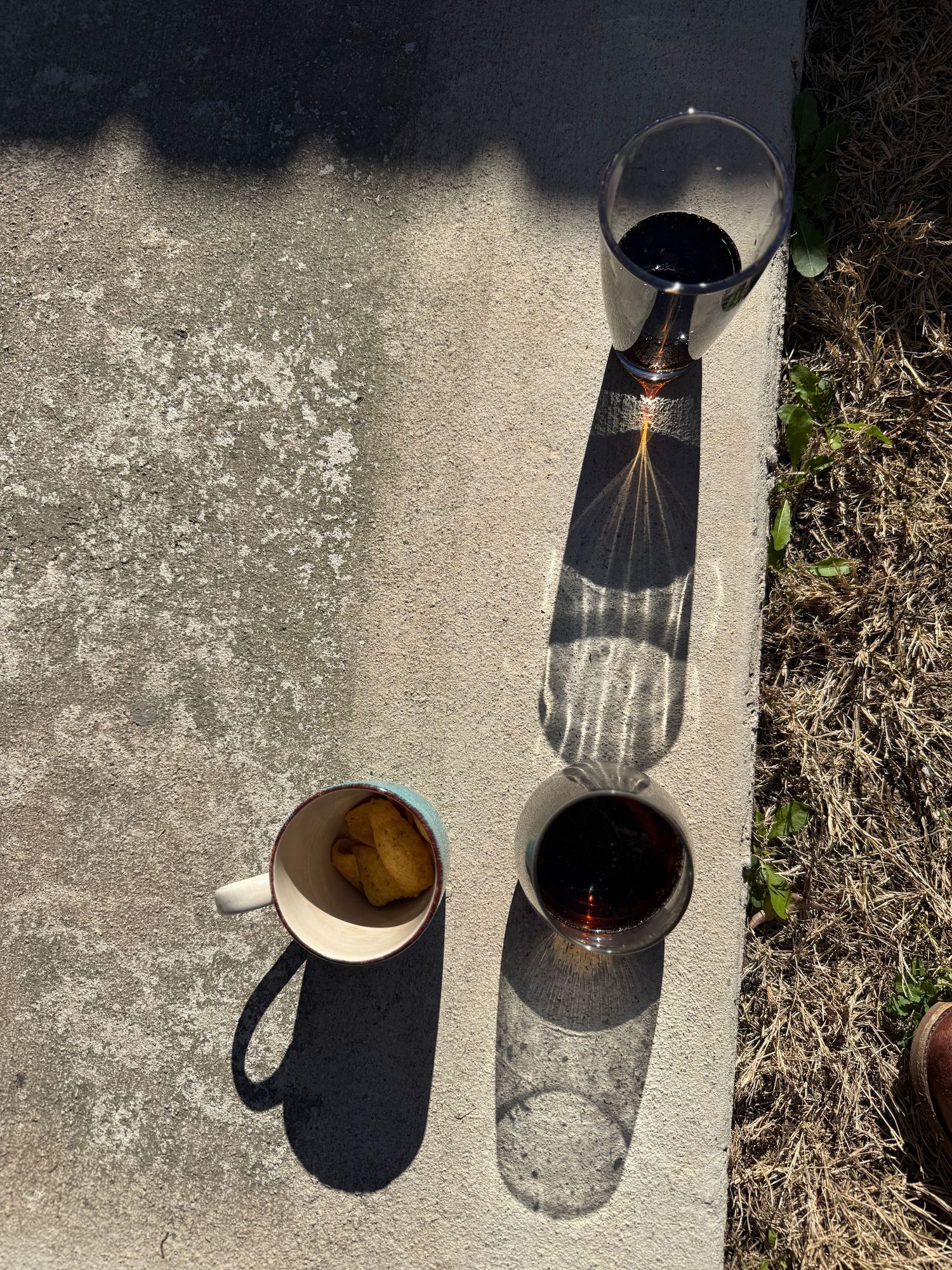 A glass cup casting a dark shadow on concrete, shown in a series of photos with changing light angles and positions.