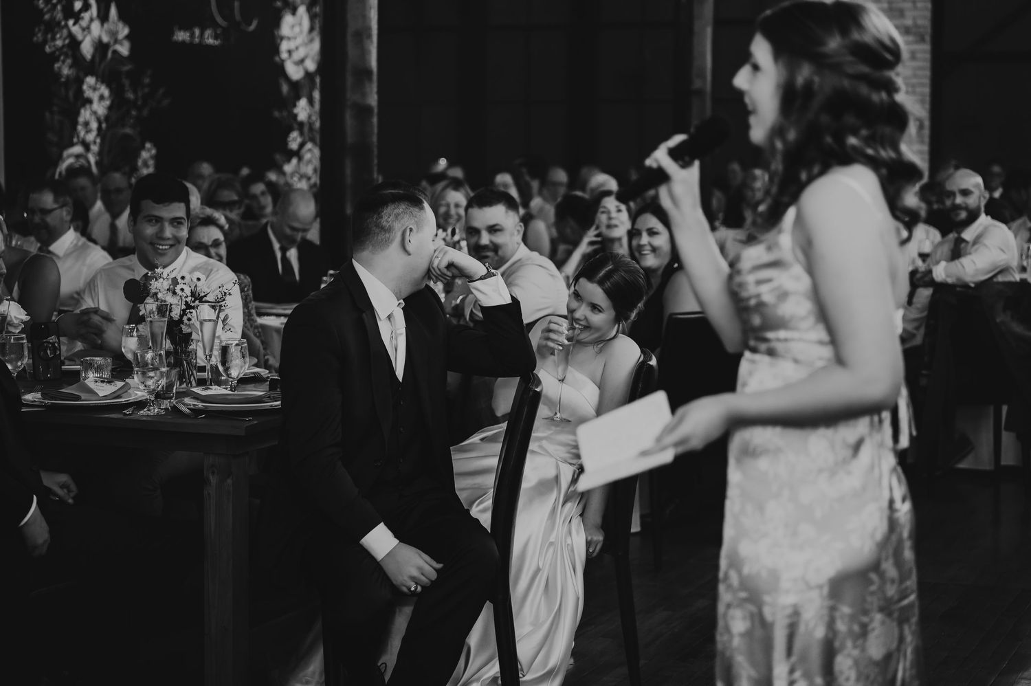 Newlywed couple sharing a romantic moment in a vintage blue car, groom in gray tuxedo kissing bride in white halter gown.