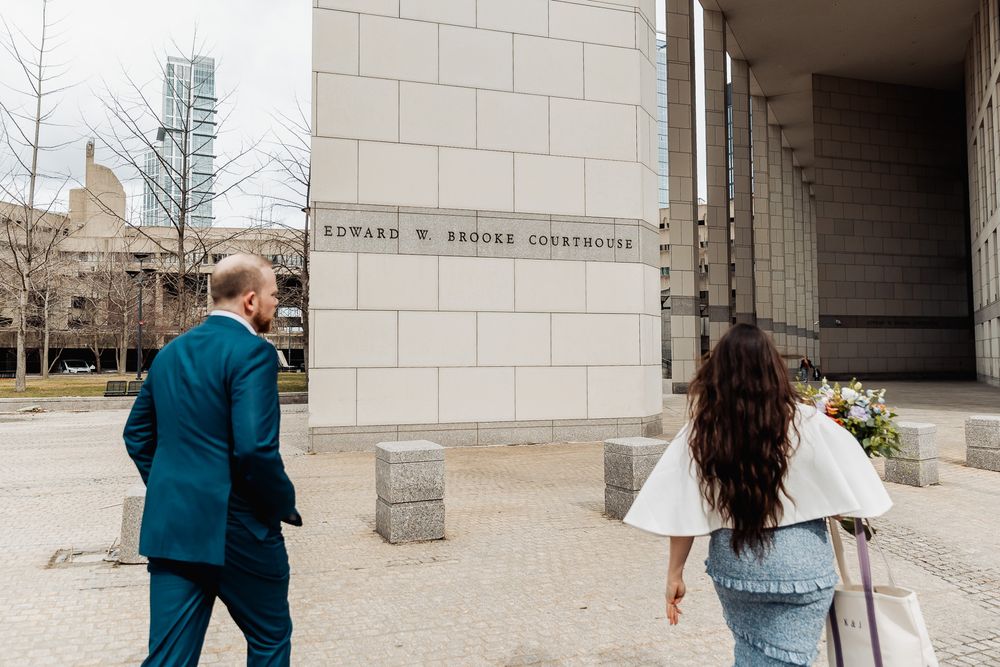 Couple walking toward Edward W. Brooke Courthouse entrance on their wedding day in Boston.