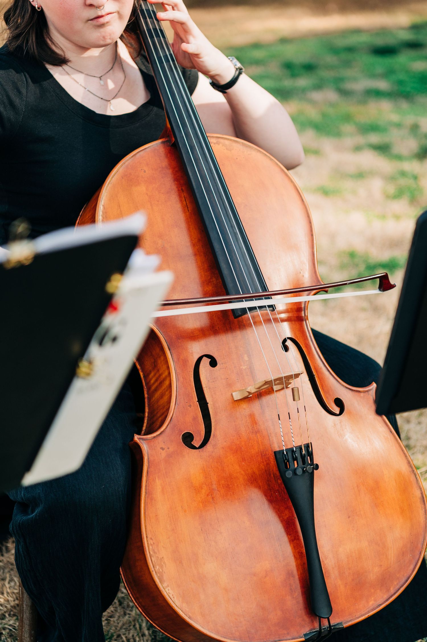 Close-up view of a cello being played outdoors, showing the rich wooden texture and f-holes of the instrument.