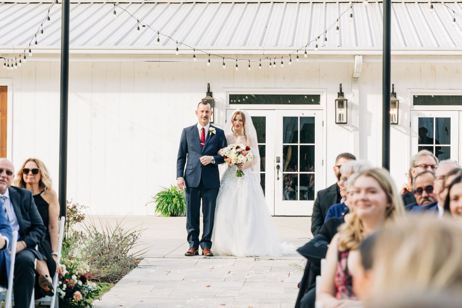 Wedding guests form a line to blow bubbles as the newlyweds walk through during an outdoor celebration.