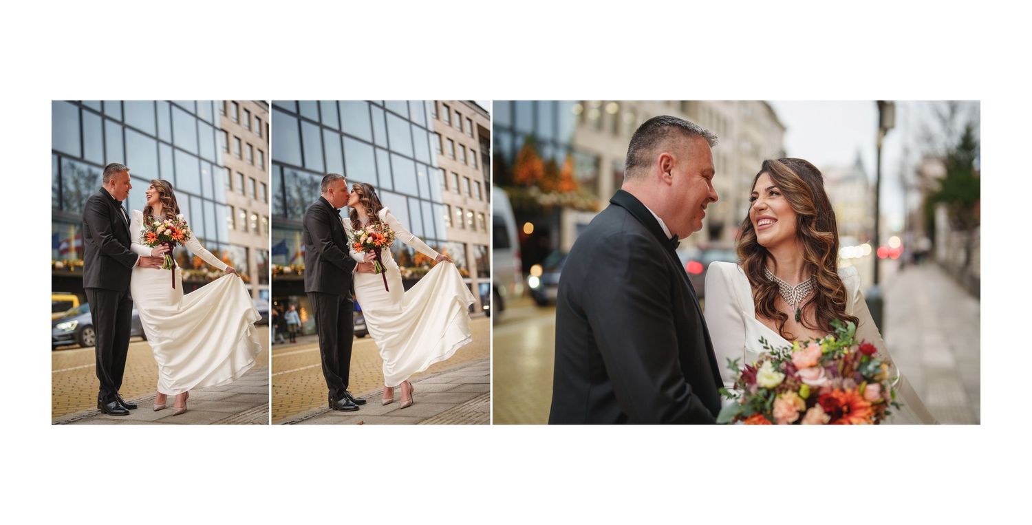 A romantic wedding couple poses for portraits on a city sidewalk with the bride holding a vibrant floral bouquet.