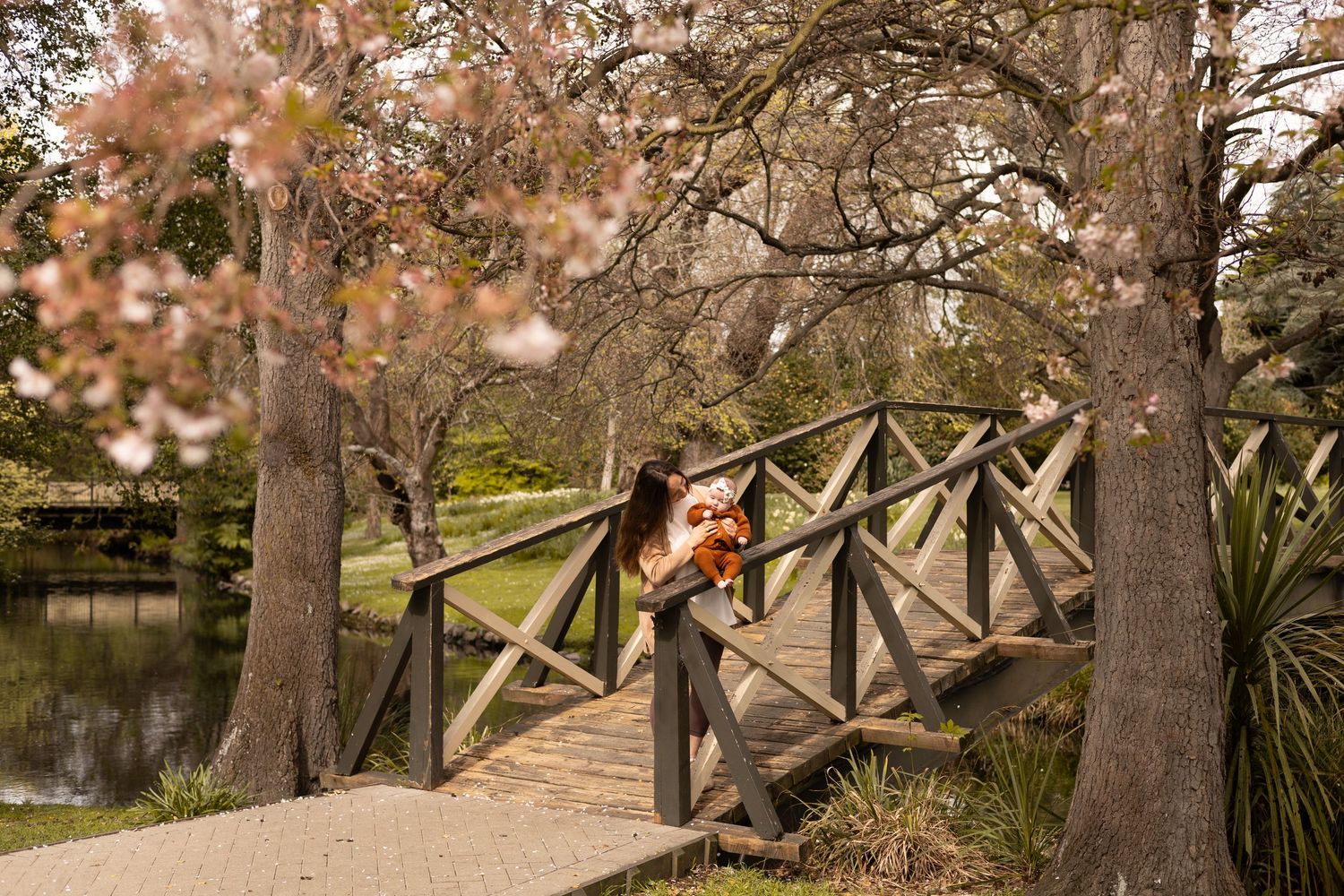 mum holding her baby during motherhood session at mona vale gardens in christchurch