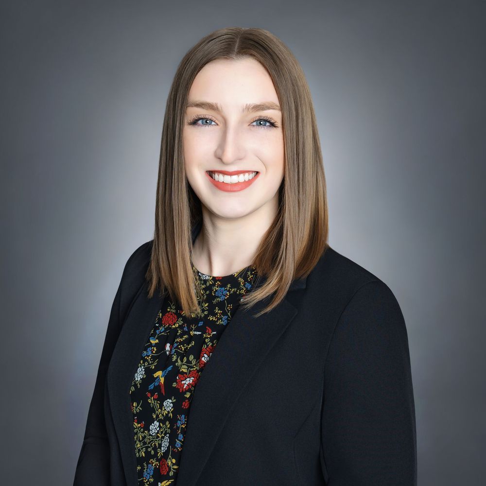 Professional headshot series showing confident woman in black blazer and dark top against gray backdrop with warm smile.