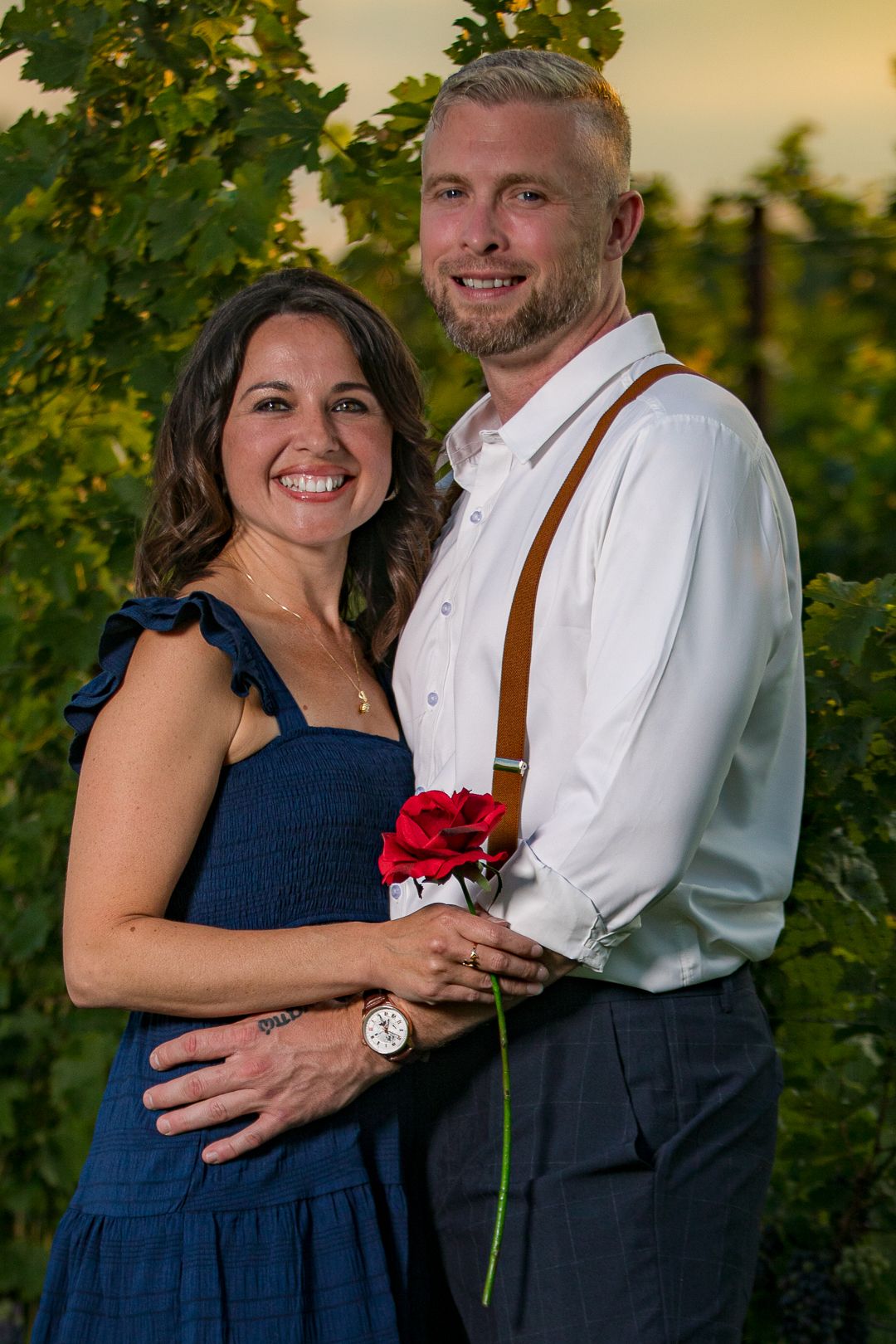 Couple shares intimate moments during golden hour sunset photoshoot in a grassy outdoor setting.