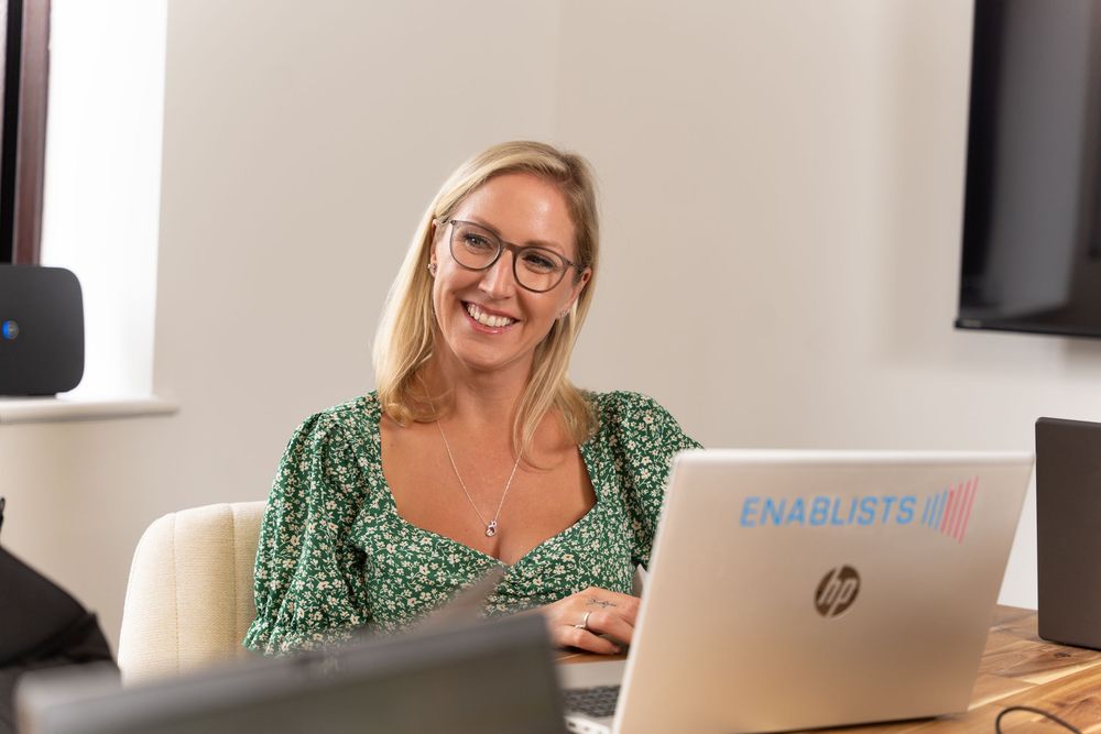 Business branding shots of a business consultant sat in a boardroom meeting with a laptop. She's smiling.