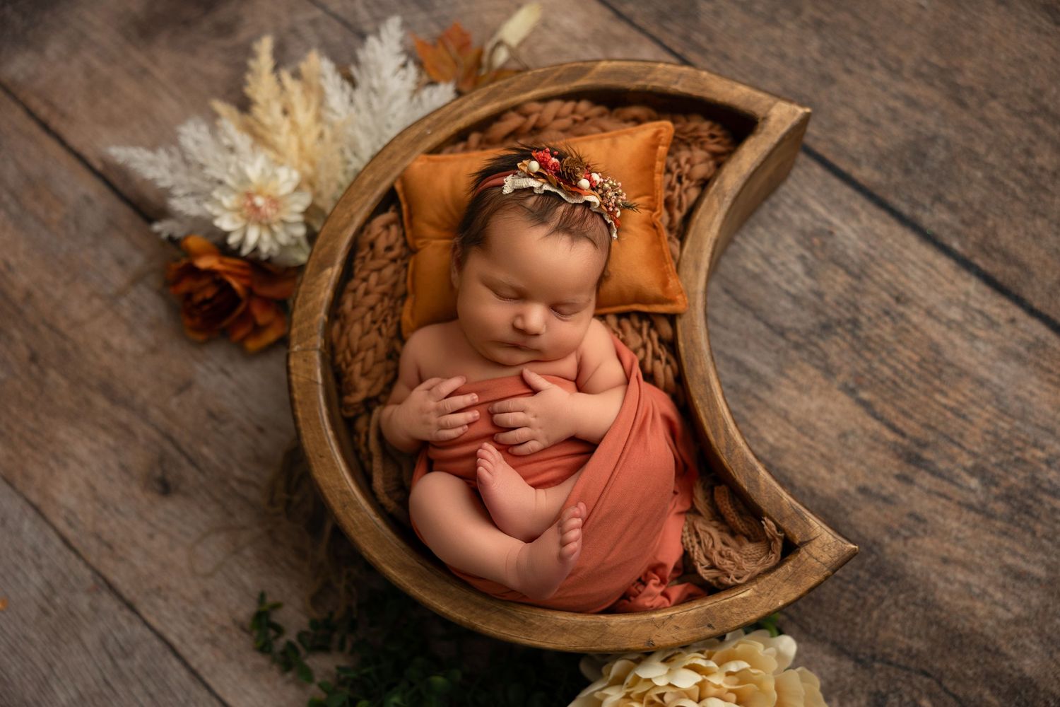 Newborn photography series showing baby in wooden bowl with autumn leaves and soft lighting on rustic wooden backdrop.