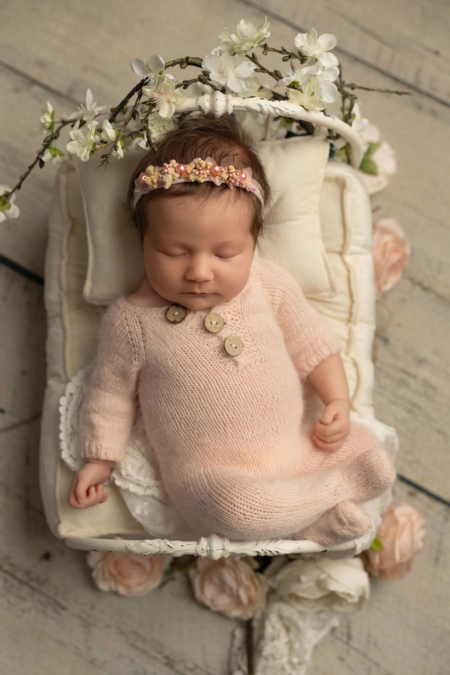 Newborn photography series showing baby in soft pink outfit with floral crown lying on white cushion from different angles.