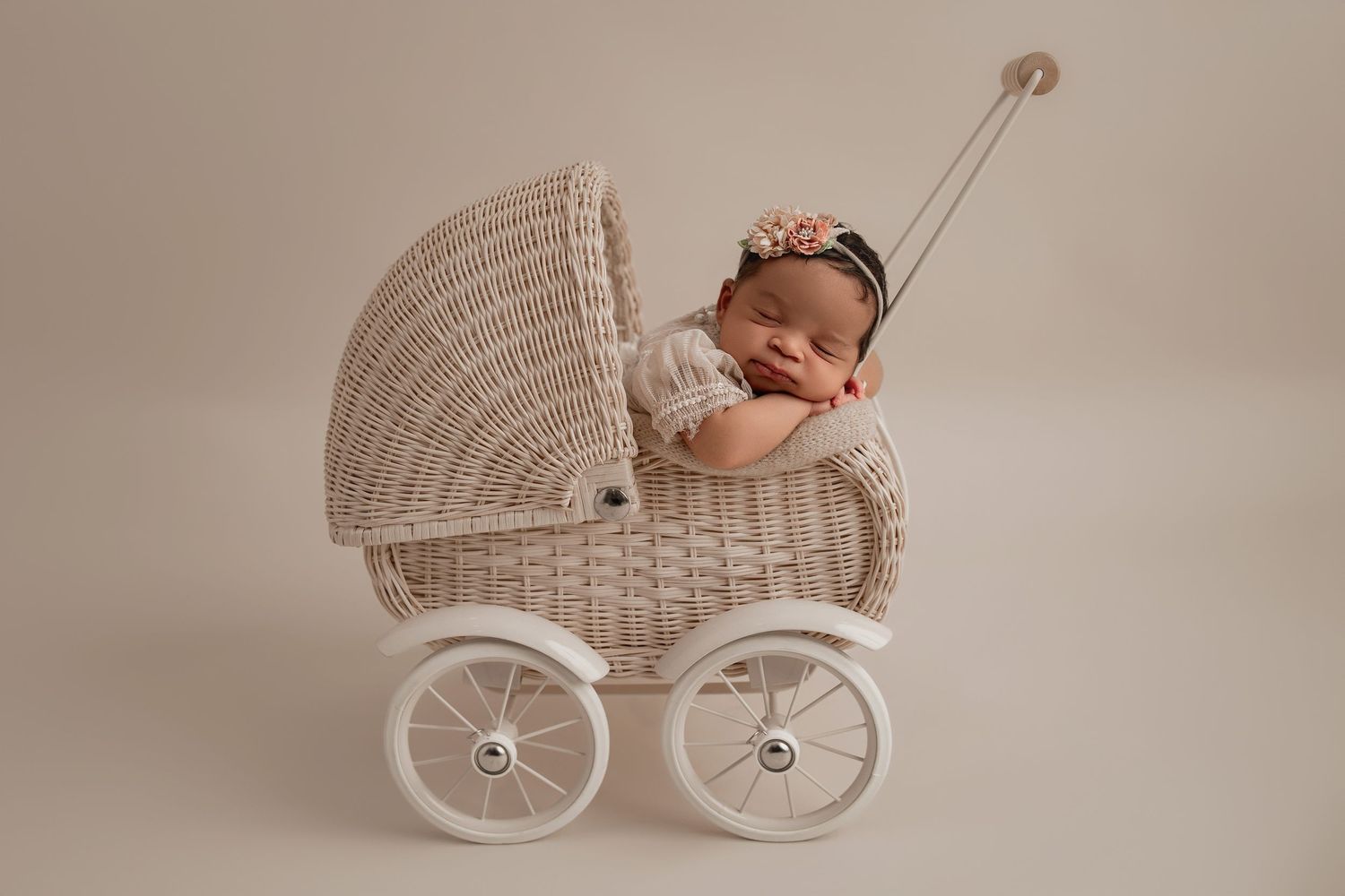 A series of vintage-style white wicker baby carriages arranged in a row on a neutral beige background.