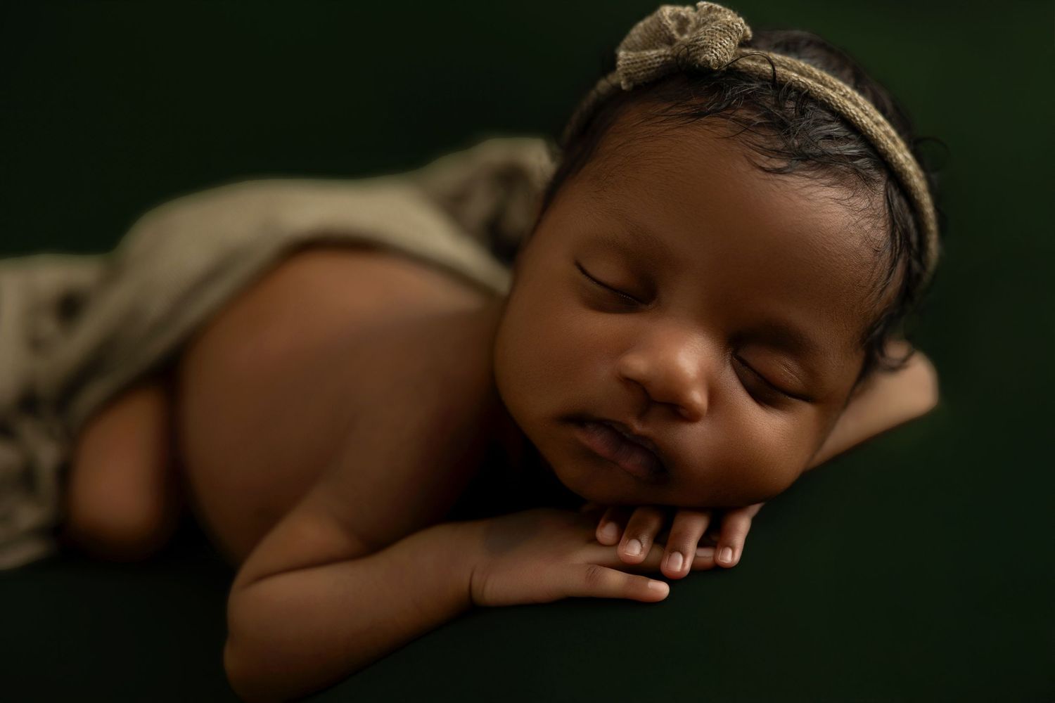 Peaceful sleeping newborn baby rests on dark background during professional photography session.
