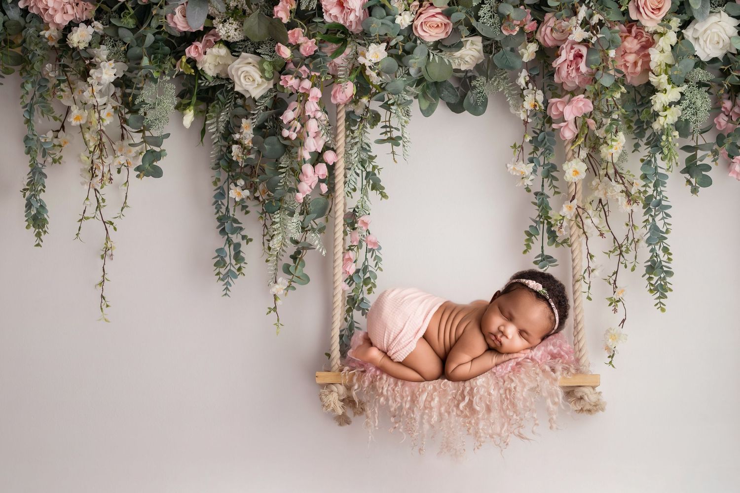 Floral garland with pink roses and greenery hangs elegantly against a light gray wall.