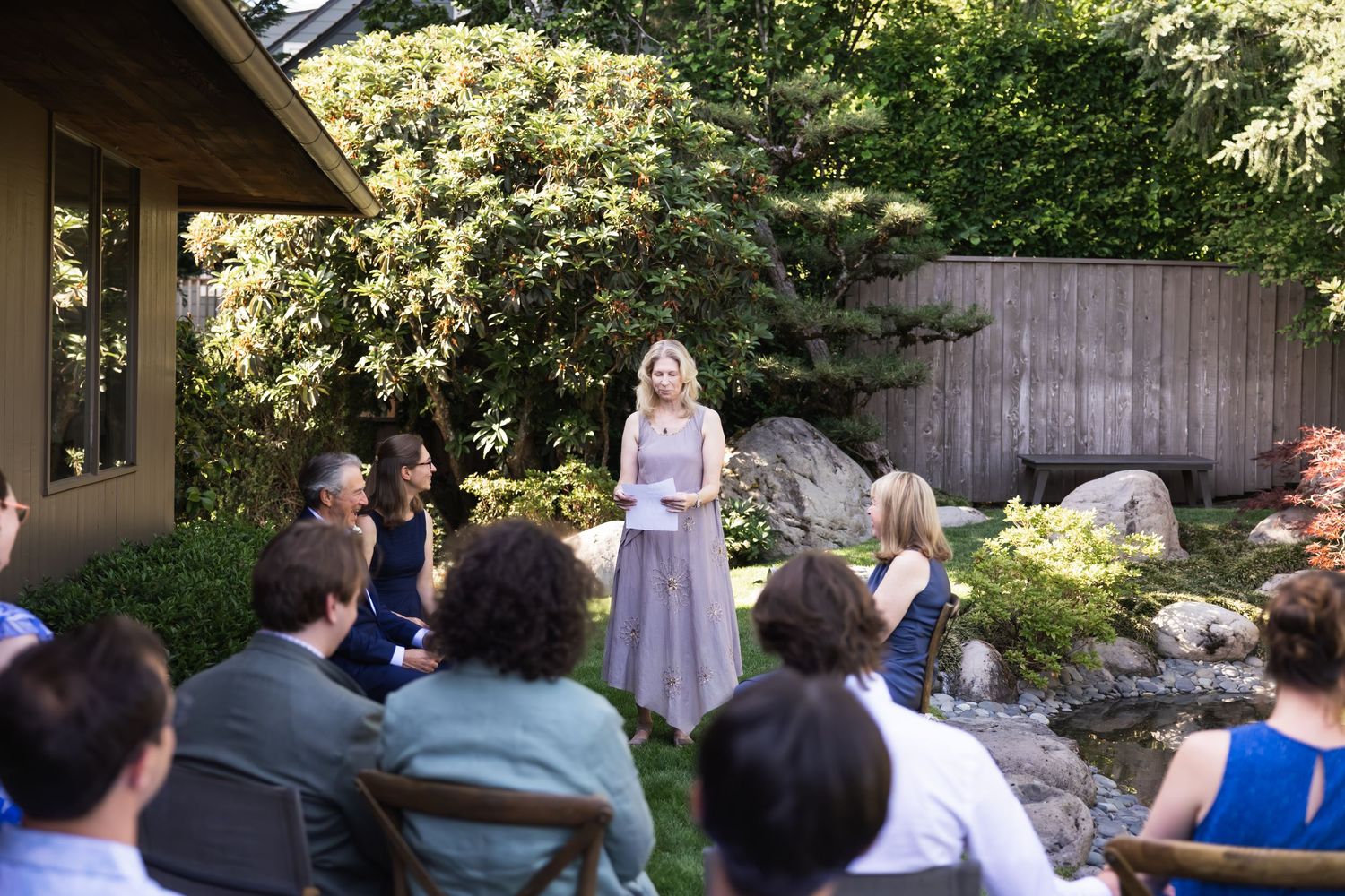 Wedding guests seated at long wooden tables on an outdoor deck overlooking scenic mountain views during sunset.