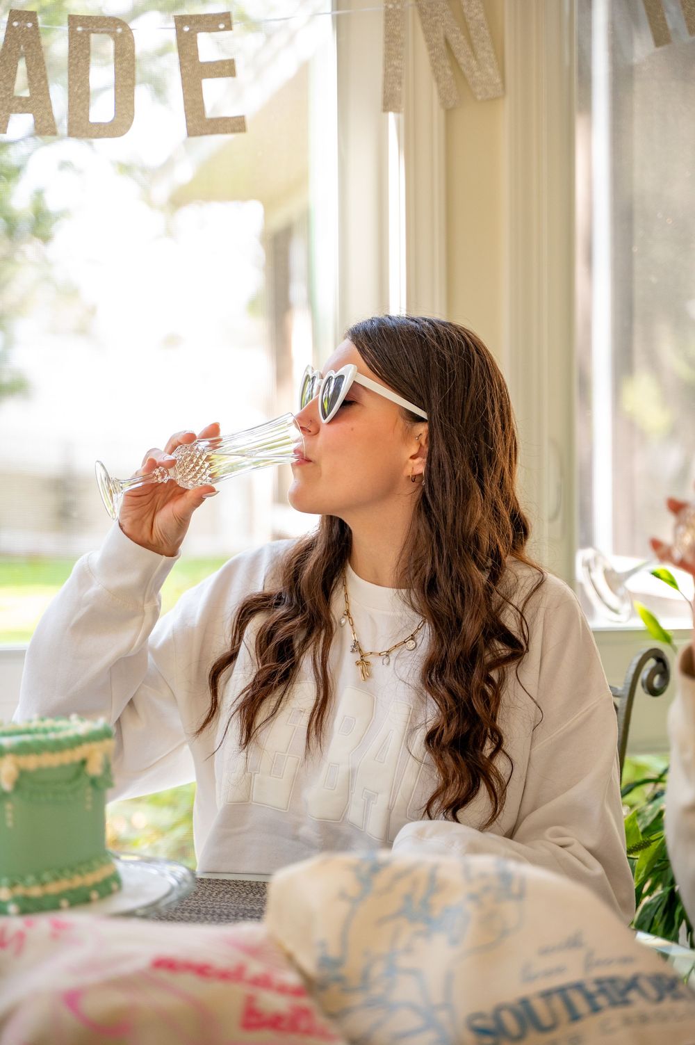 A series of photos showing someone drinking from a teacup while sitting in a bright sunlit room with decorative pillows.