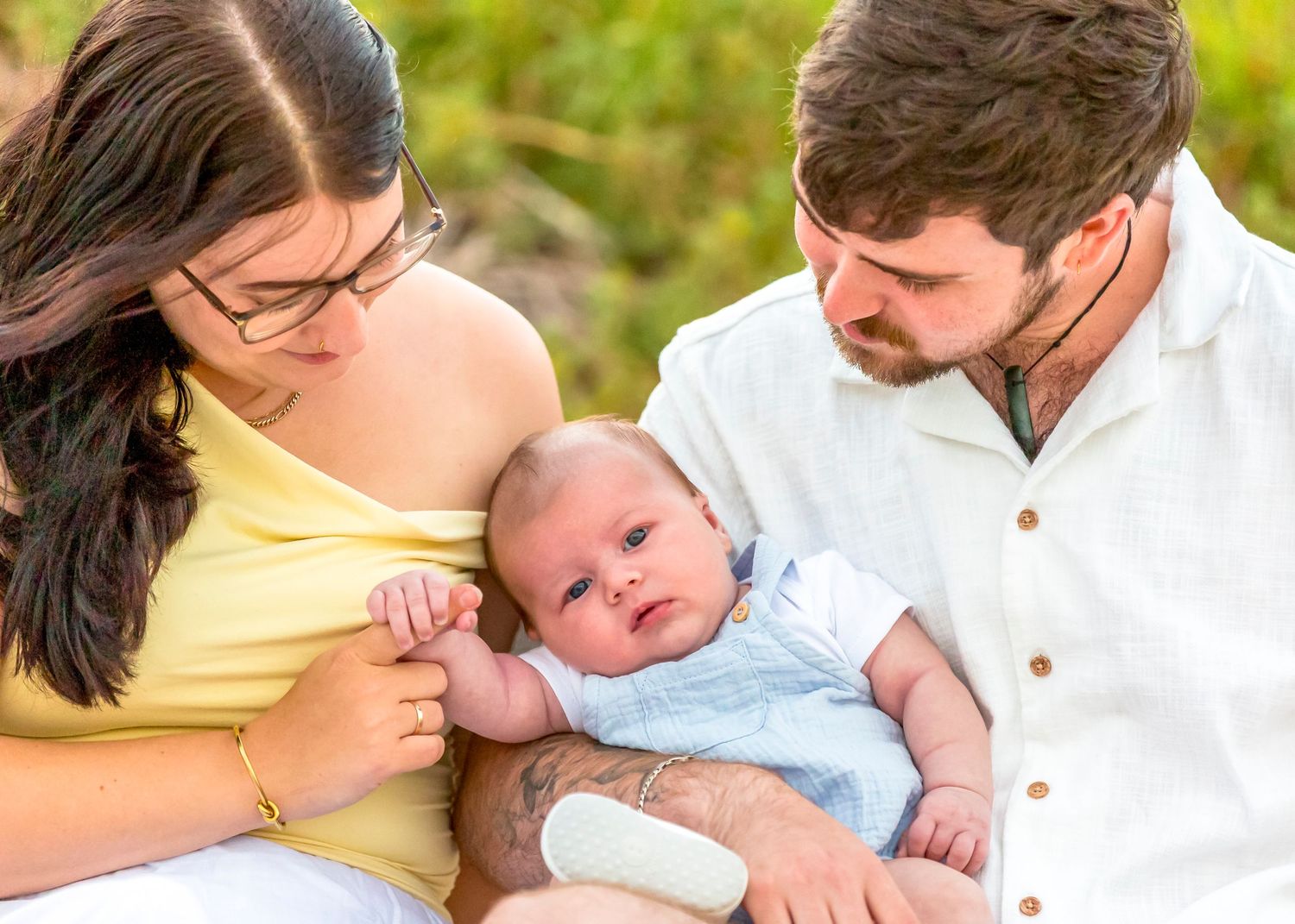 Outdoor family photo with young baby, captured naturally with soft light and no posing.