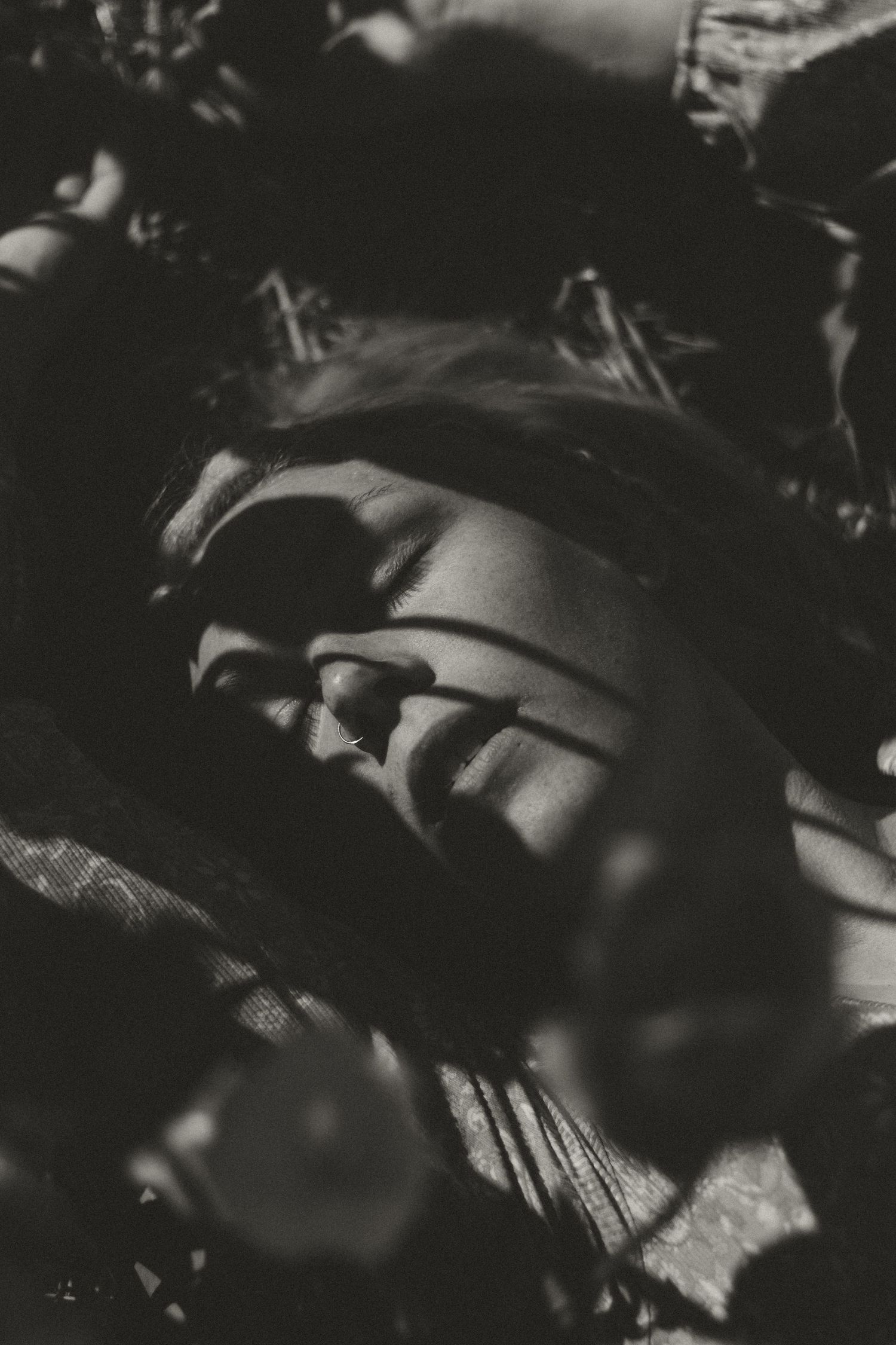 Artistic black and white portrait showing dramatic shadows falling across a resting figure.