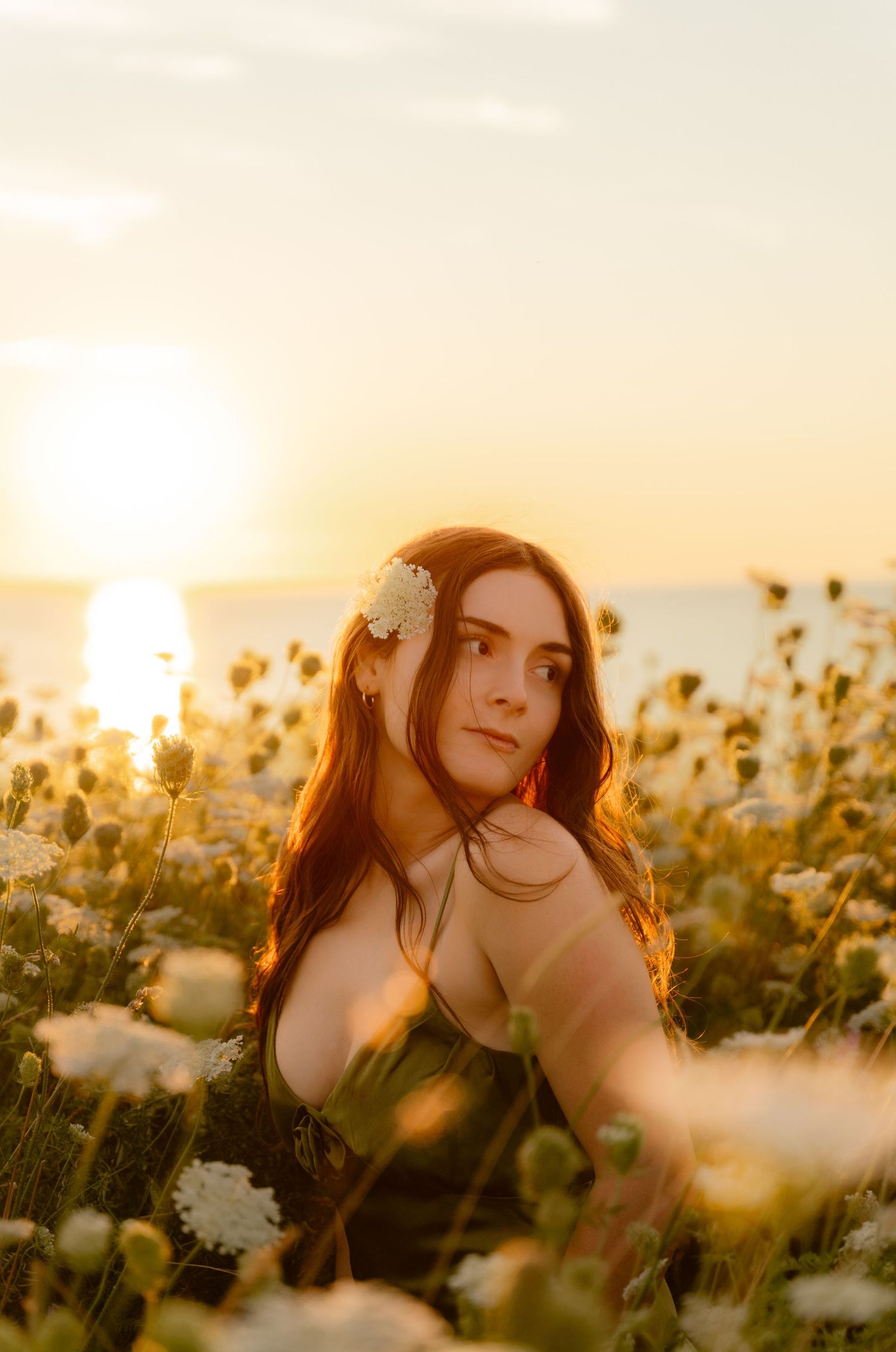 Dreamy sunset portrait among blooming wildflowers with golden backlight.