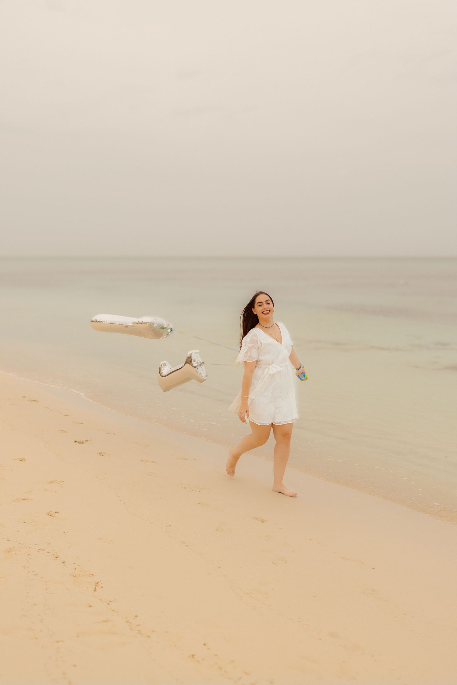 Joyful moment captured on beach with floating shoes and white dress.