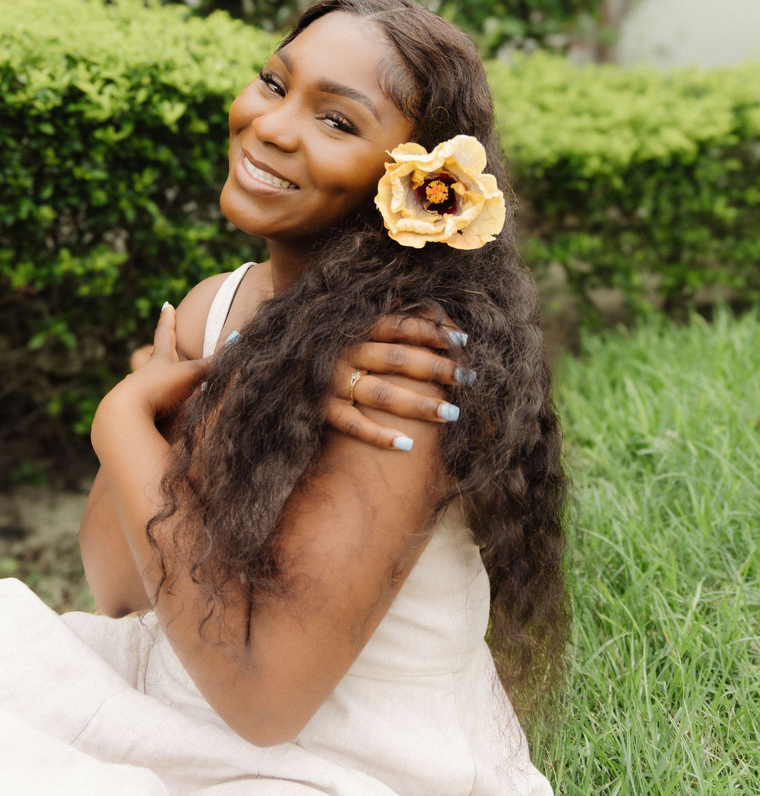Portrait with peach flower accessory against lush green garden background.