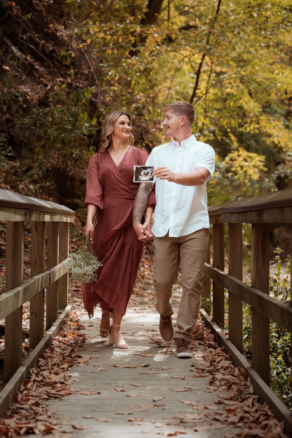 Expecting couple walking across a wooden bridge during a fall maternity session.