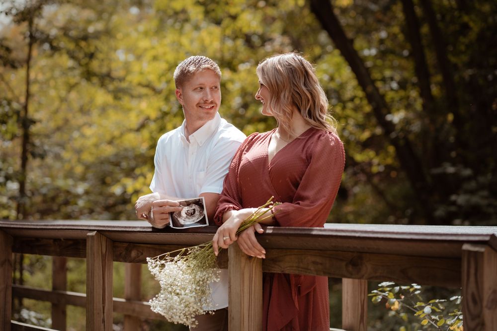 Expecting couple holding ultrasound photo during an outdoor maternity session.