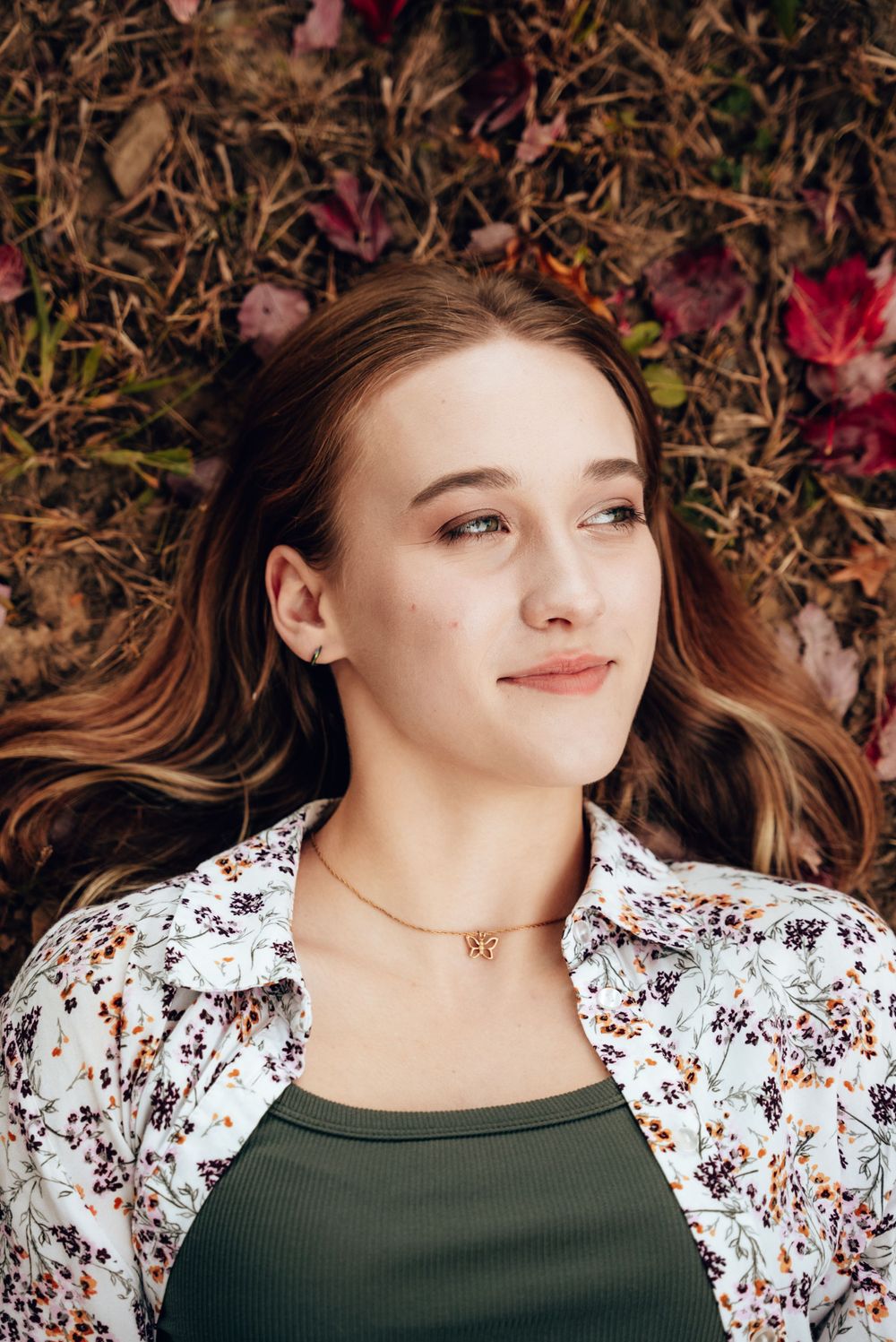 Natural portrait of young woman lying among autumn leaves.