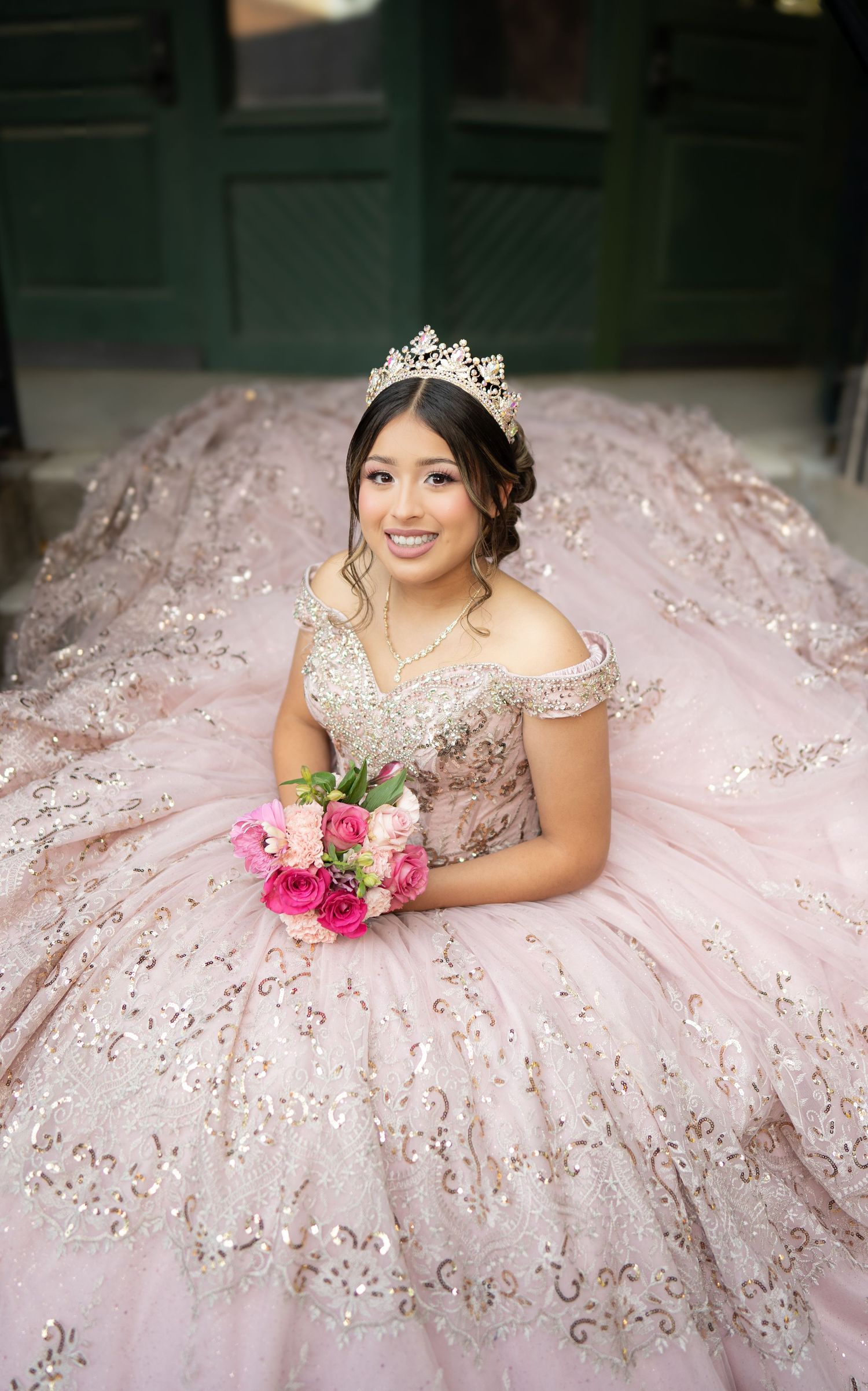Overhead portrait of a person in an elegant cream dress holding a teal bouquet.