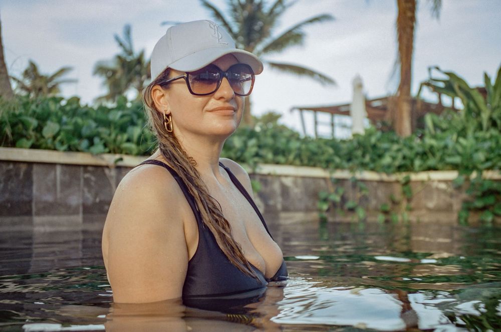 A relaxing pool scene with palm trees and tropical landscaping in the background.