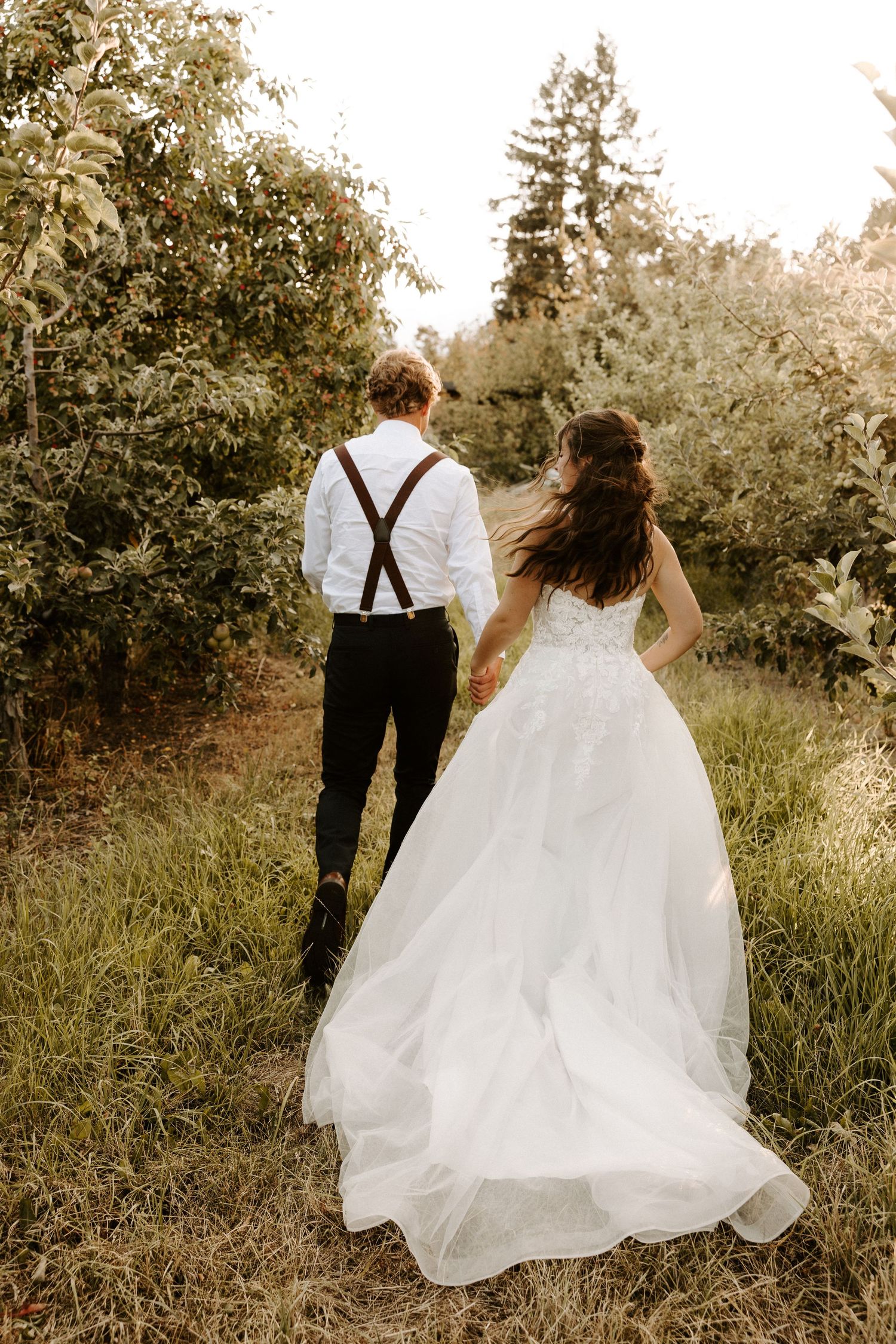 Couple in wedding attire sharing intimate moment in a lush forest setting.