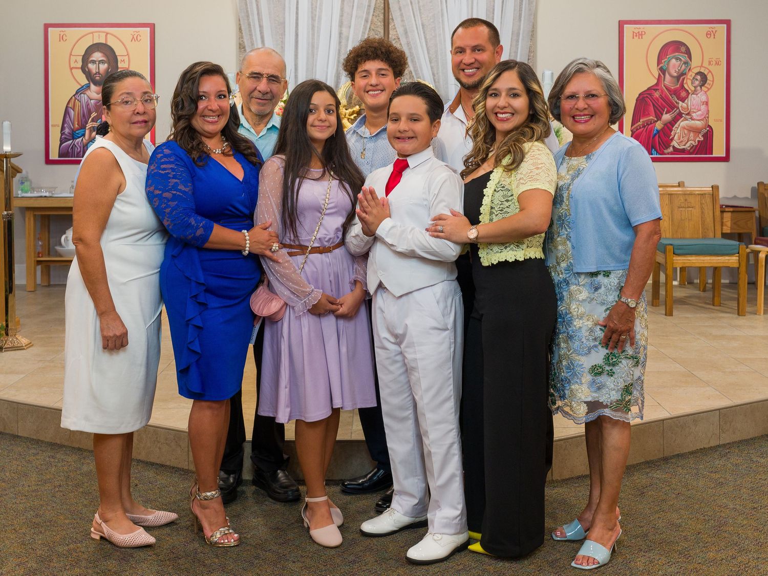 Large group portrait of families and children posed in front of religious artwork.